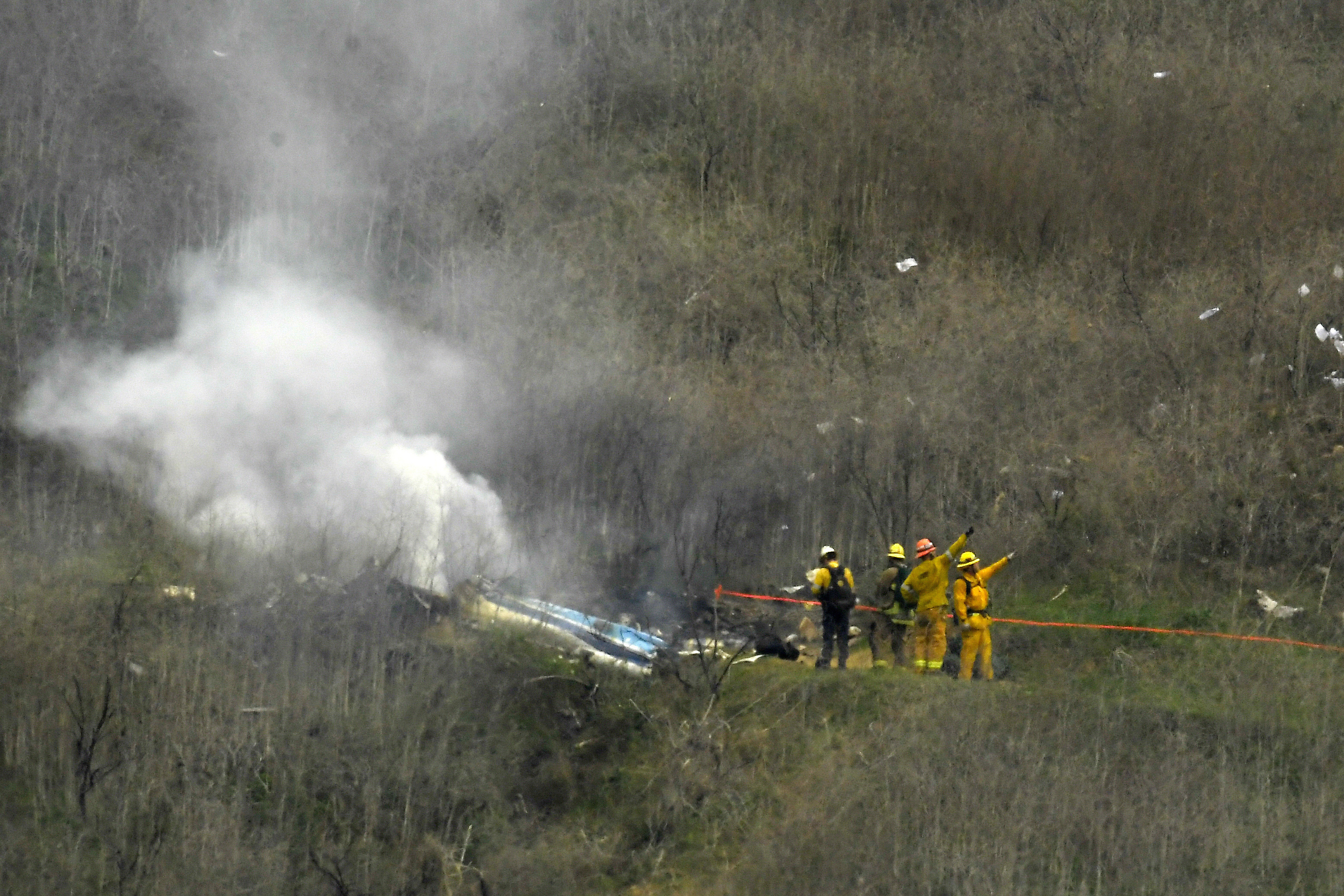 FILE - Firefighters work the scene of a helicopter crash where former NBA basketball star Kobe Bryant died in Calabasas, Calif., Jan. 26, 2020. Bryant's widow is taking her lawsuit against the Los Angeles County Sheriff's Department and Fire Department to a federal jury seeking compensation for photos deputies shared of the remains of the NBA star, his daughter and seven others killed in a helicopter crash in 2020. 