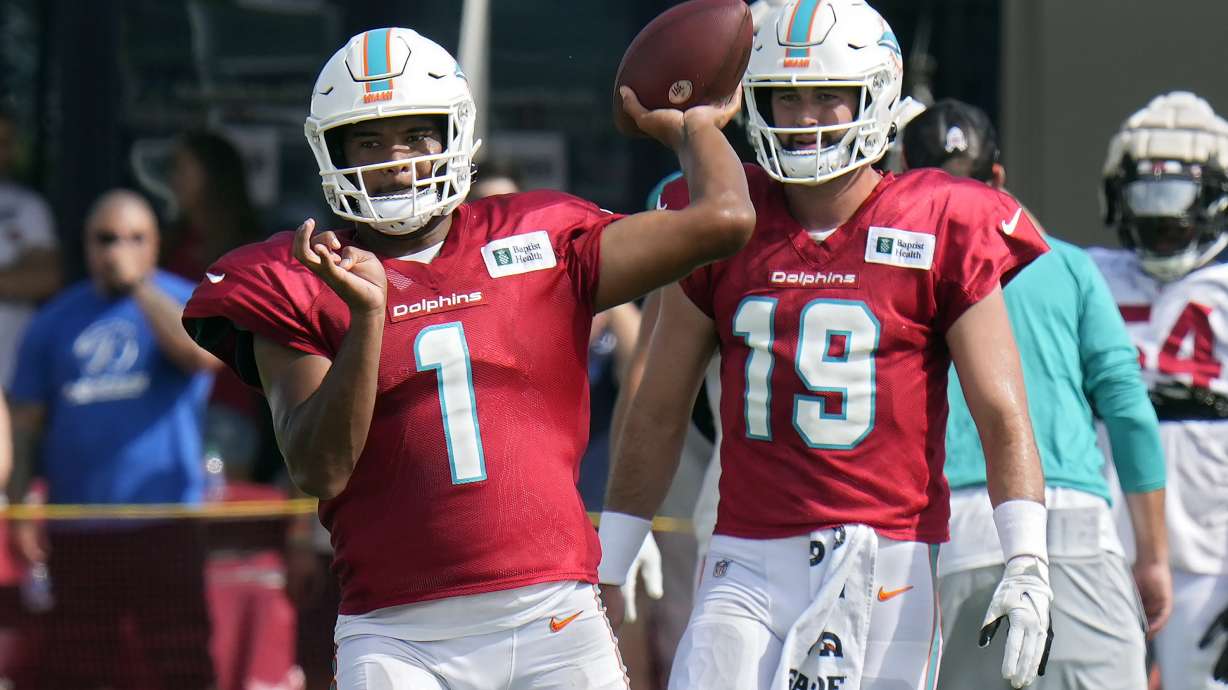 Miami Dolphins quarterback Tua Tagovailoa (1) throws a pass during an NFL football training camp practice with the Tampa Bay Buccaneers Wednesday, Aug. 10, 2022, in Tampa, Fla. Looking on is quarterback Skylar Thompson (19).