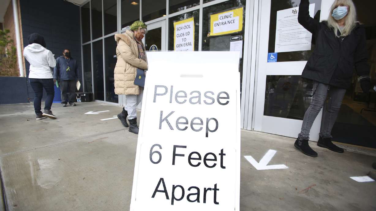 A sign asks those getting vaccinated to keep 6 feet apart during the vaccination event Jan. 27, 2021, at Nevada Union High School in Grass Valley, Calif. The CDC has again revised its COVID guidelines Thursday, further relaxing quarantine recommendations and dropping the recommendation that people stay at least 6 feet away from each other.