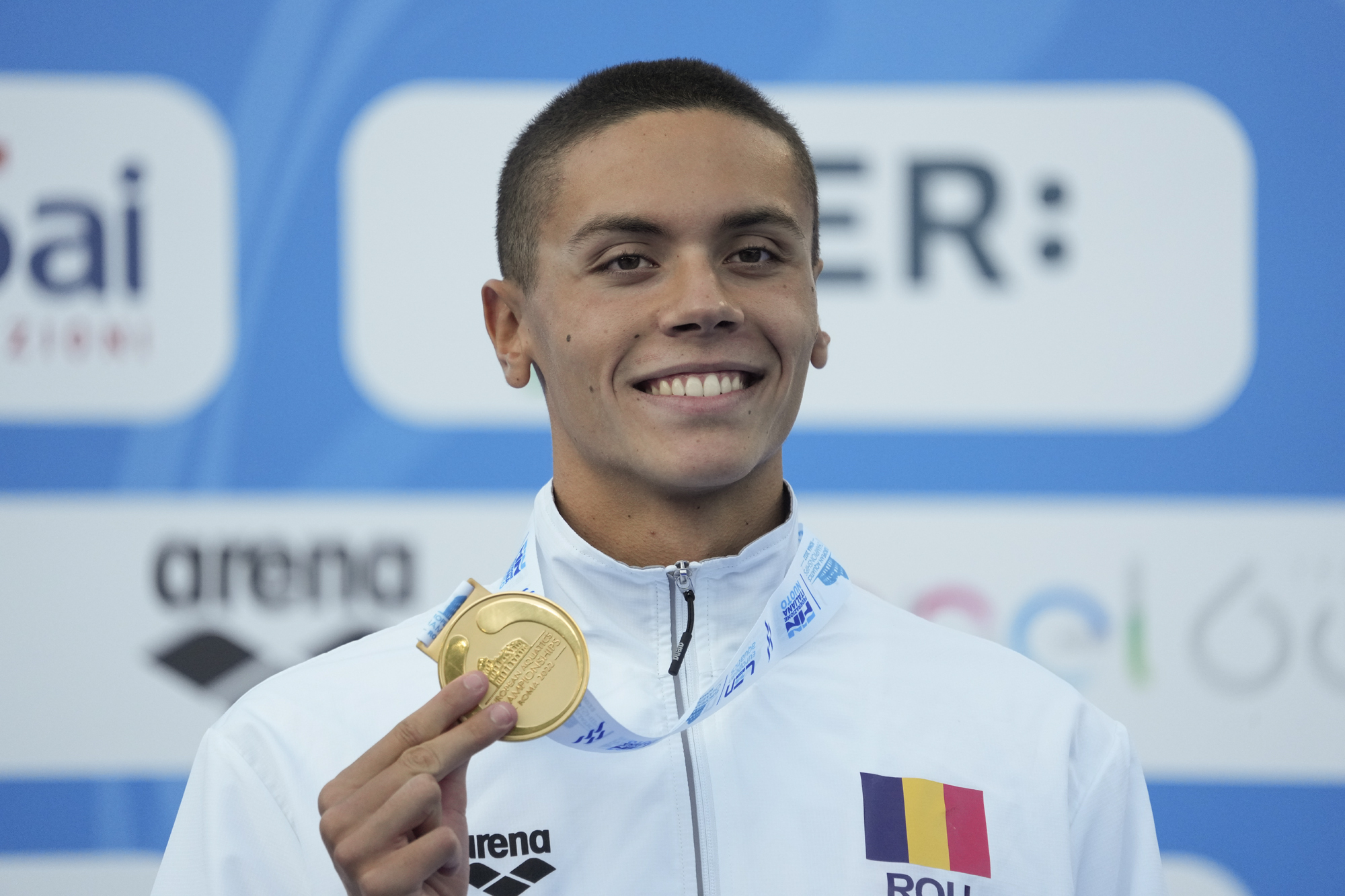 First placed Romania's David Popovici celebrates on the podium of the men's 100m freestyle final at the European swimming championships, in Rome, Saturday, Aug. 13, 2022. 