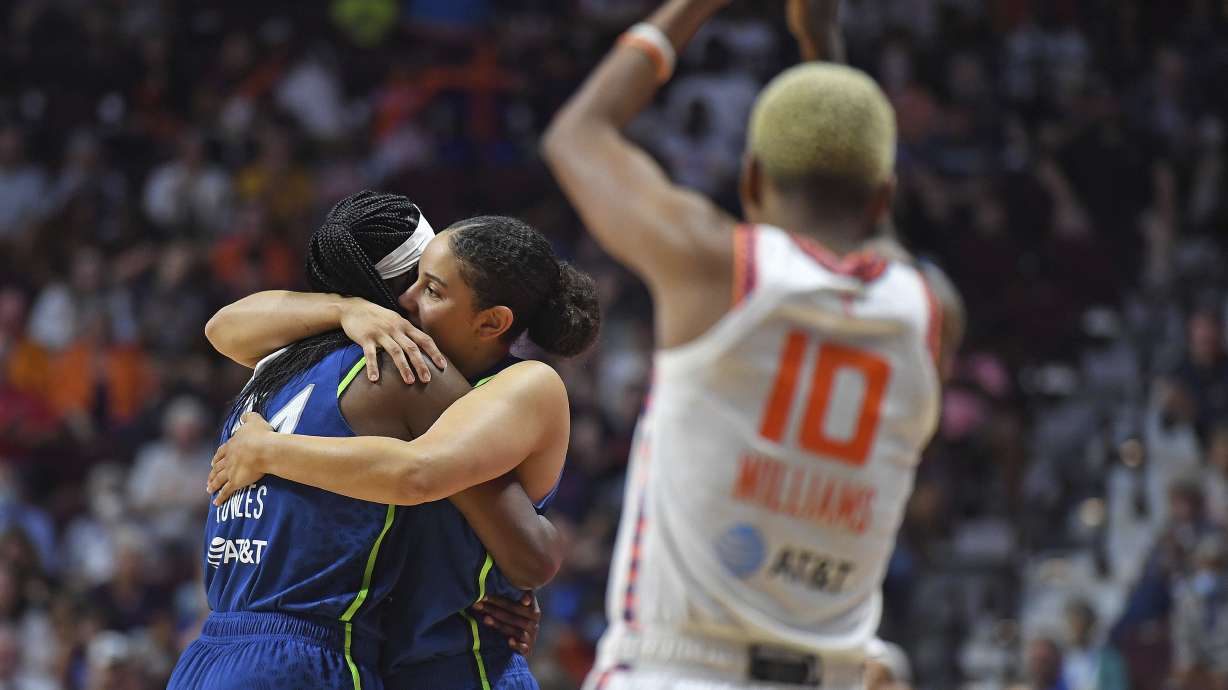 Connecticut Sun guard Courtney Williams (10) applauds as Minnesota Lynx center Sylvia Fowles, left, embraces teammate Natalie Achonwa as Fowles leaves in the closing minute o a WNBA basketball game Sunday, Aug. 14, 2022, in Uncasville, Conn. Fowles played her final game as the Sun eliminated the Lynx from playoff contention.