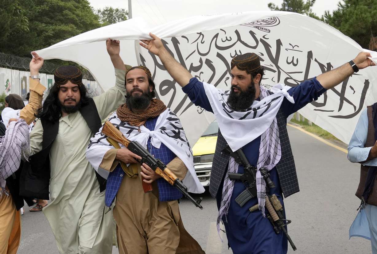 Taliban fighters hold their flag as they celebrate one year since they seized the Afghan capital, Kabul, in front of the U.S. Embassy in Kabul, Afghanistan, Monday.