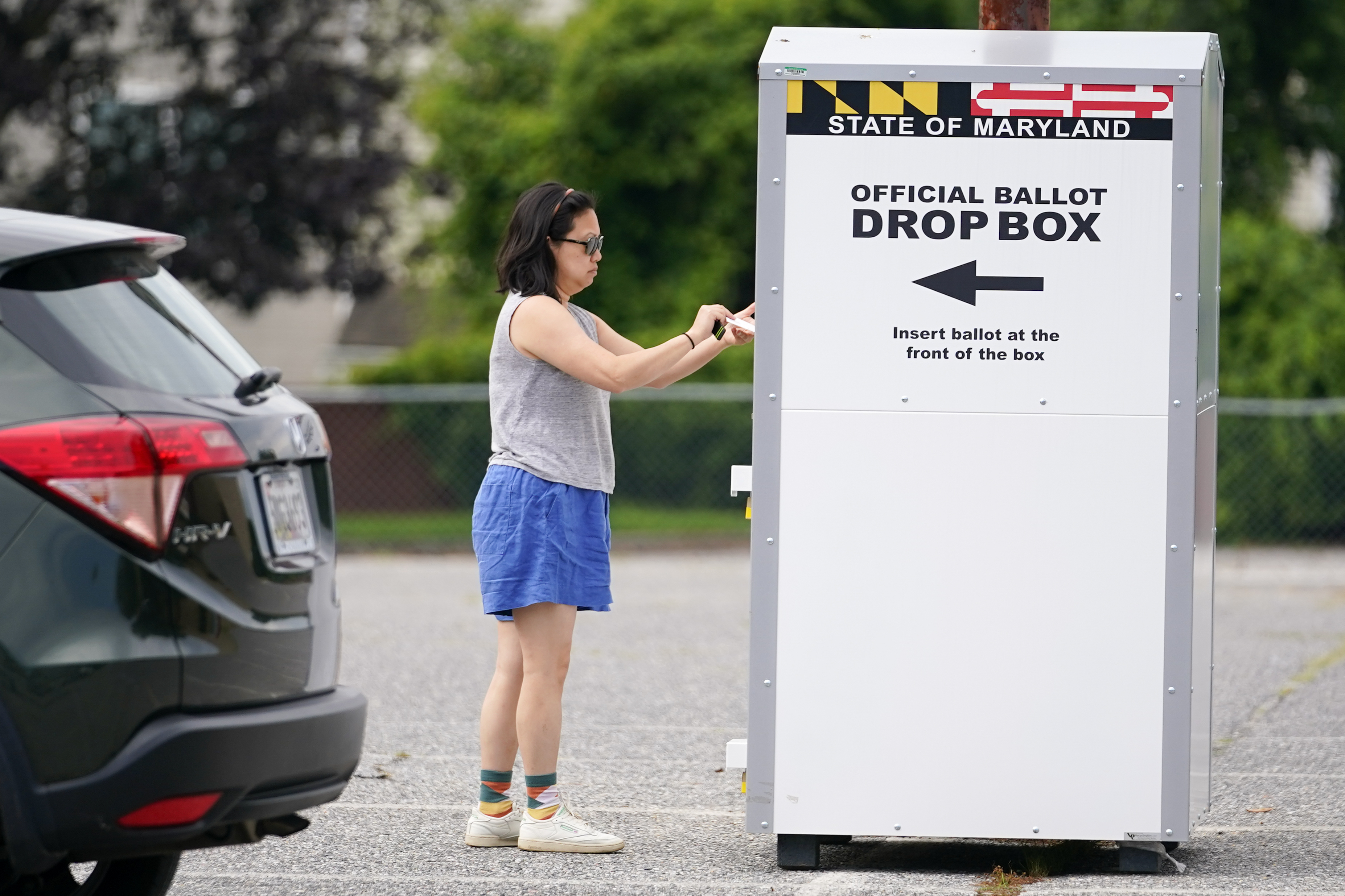 FILE - A woman drops a ballot into a drop box while casting her vote during Maryland's primary election, Tuesday, July 19, 2022, in Baltimore. The Maryland State Board of Elections voted Monday, Aug. 15, 2022, to file an emergency petition in court that seeks an earlier count of mail-in ballots for the general election in November. 