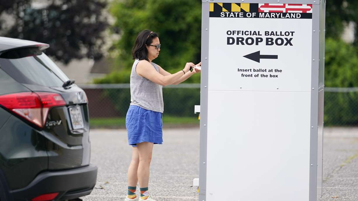 FILE - A woman drops a ballot into a drop box while casting her vote during Maryland's primary election, Tuesday, July 19, 2022, in Baltimore. The Maryland State Board of Elections voted Monday, Aug. 15, 2022, to file an emergency petition in court that seeks an earlier count of mail-in ballots for the general election in November.