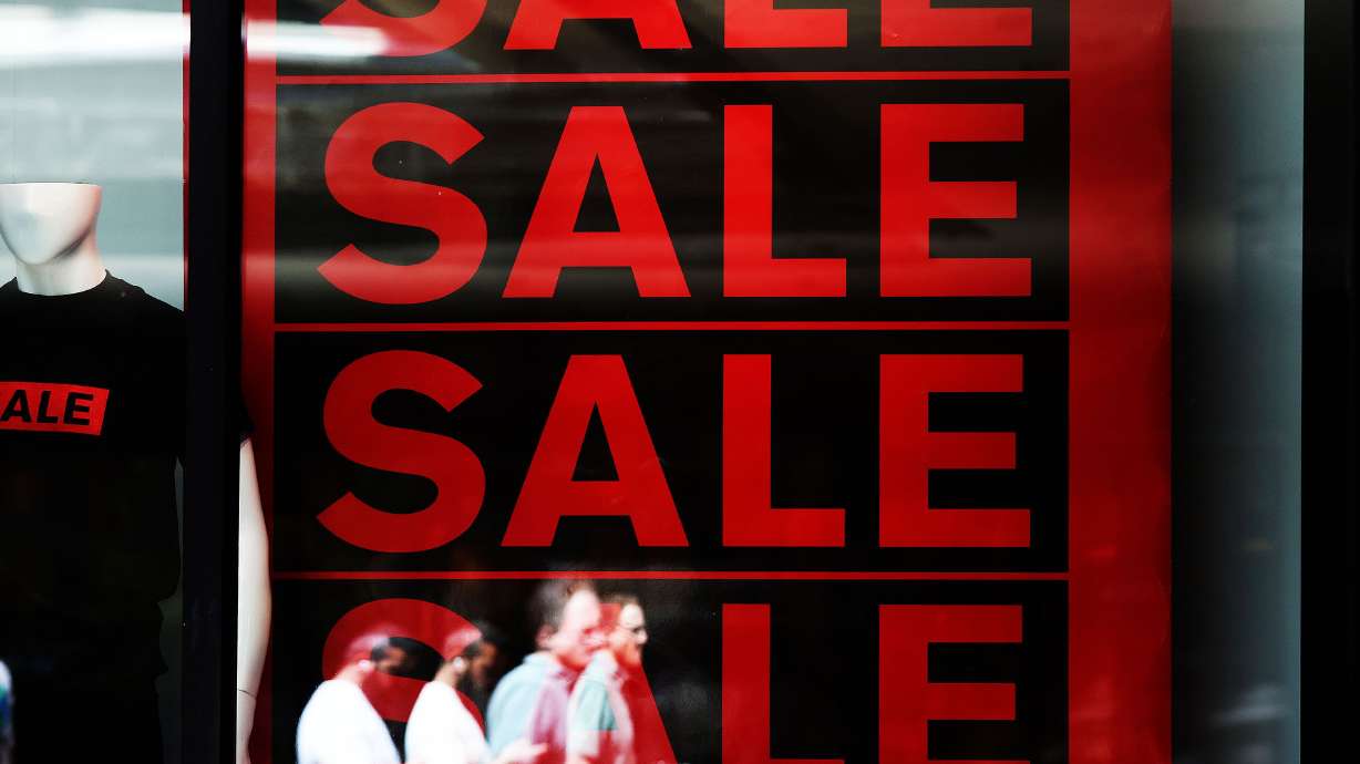 Shoppers walk by a sale sign at Express Men in City Creek Center in Salt Lake City on Wednesday. A Census Bureau report shows U.S. consumer spending continues to run at record volume in spite of persistent, record-high inflation.