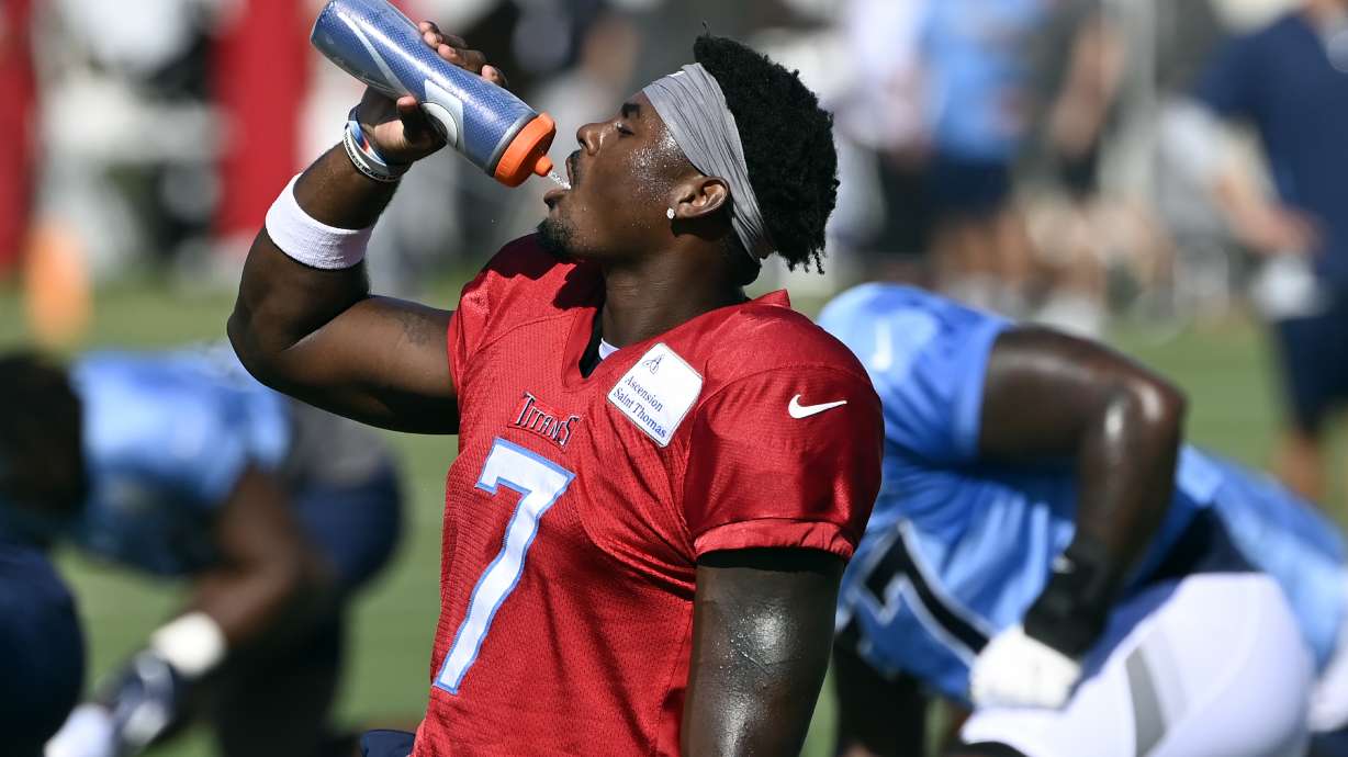 Tennessee Titans quarterback Malik Willis (7) gets a drink during a combined NFL football training camp with the Tampa Bay Buccaneers, Thursday, Aug. 18, 2022, in Nashville, Tenn.