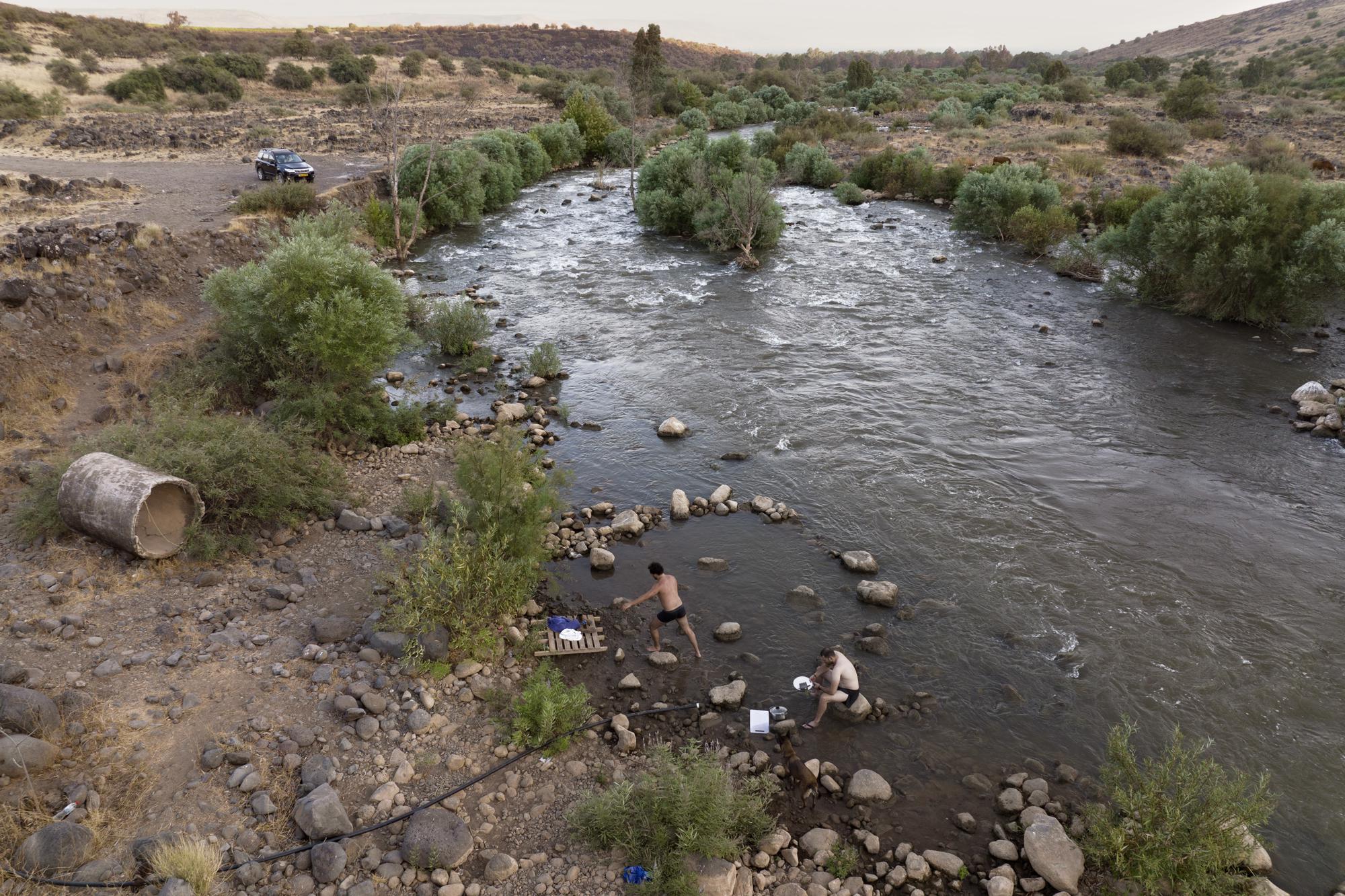 People bathe in the Jordan River near Kibbutz Karkom in northern Israel on July 30. The river's decline is intertwined with the decades-old Arab-Israeli conflict and rivalries over precious water supplies in an area where so much is contested.