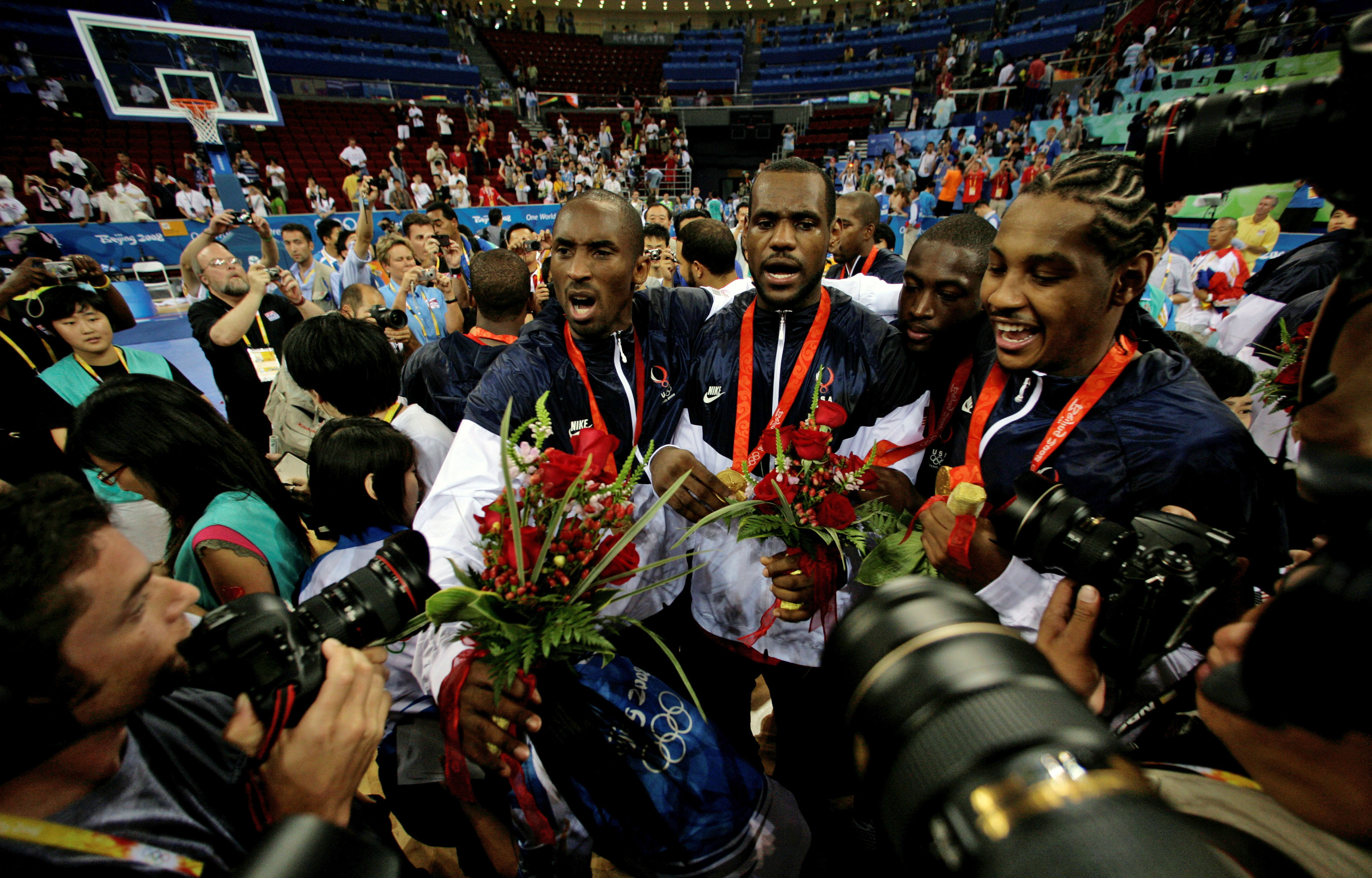 FILE - Kobe Bryant, from left, LeBron James, Dwyane Wade and Carmelo Anthony, of the U.S. Olympic basketball team, are surrounded by photographers as they celebrate after beating Spain 118-107 in the men's gold medal basketball game at the Beijing 2008 Olympics in Beijing. A documentary on the 2008 U.S. men’s basketball team known as the “Redeem Team,” with executive producers including Lebron James and Dwayne Wade, will premiere on Netflix in October. 