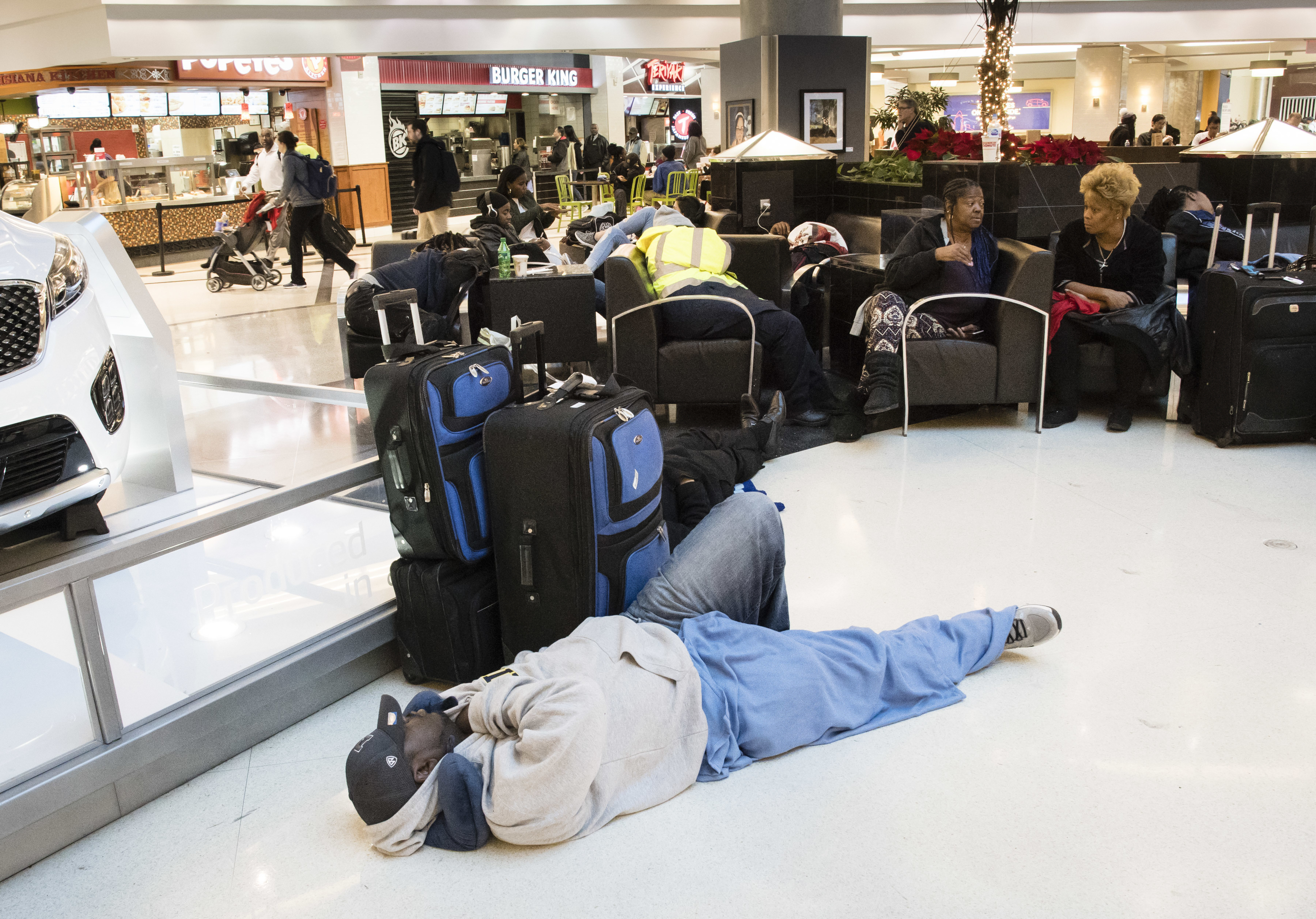 A man sleeps on the terminal floor at Hartfield-Jackson Atlanta International Airport on Dec. 18, 2017, in Atlanta. Transportation Secretary Pete Buttigieg has warned airlines that his department could draft new rules around passenger rights if the carriers don’t give more help to travelers trapped by flight cancellations and delays.