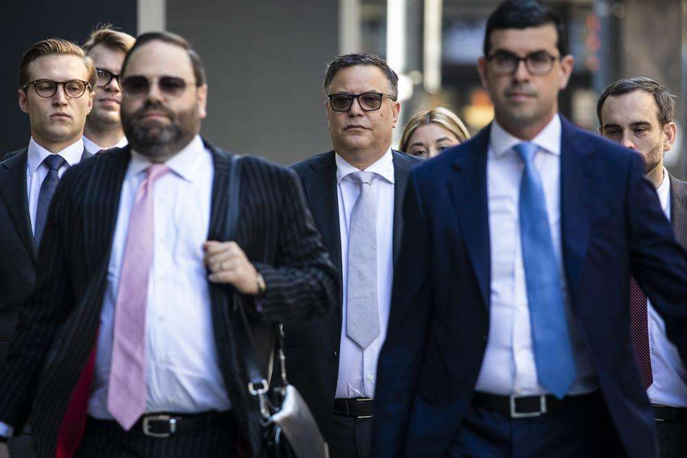 Flanked by attorneys, Derrel McDavid, center, walks into the Dirksen Federal Courthouse in Chicago as opening statements were expected to begin in R. Kelly's trial, Wednesday morning. Two Kelly associates, Derrel McDavid and Milton Brown, are co-defendants. McDavid is accused of helping Kelly fix the 2008 trial, while Brown is charged with receiving child pornography. Like Kelly, they also have denied wrongdoing.