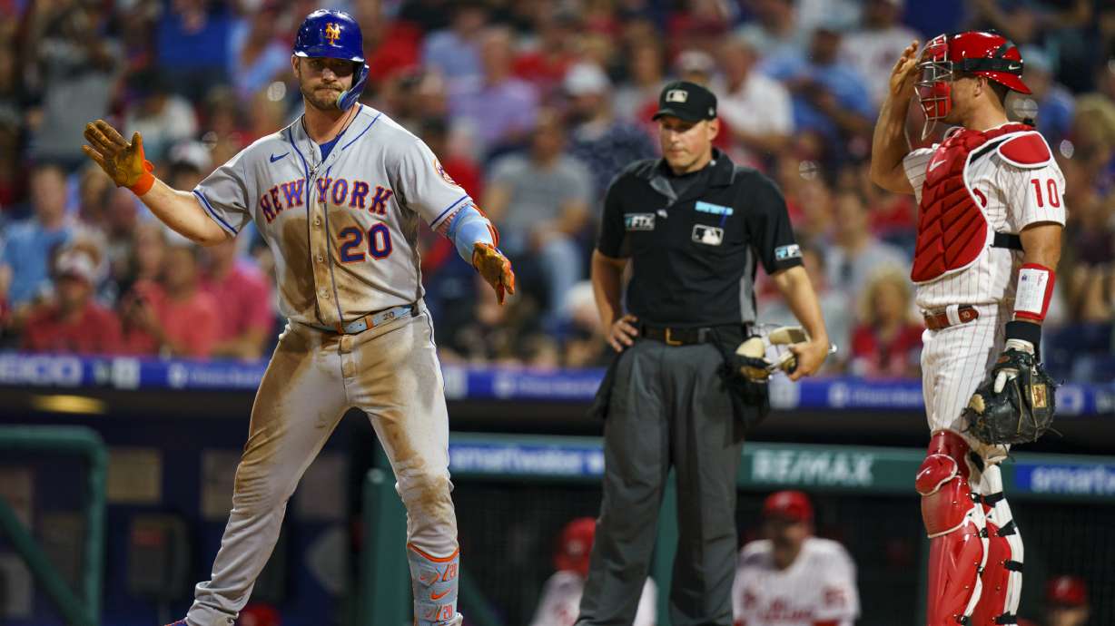 New York Mets' Pete Alonso, left, reacts to his home run as Philadelphia Phillies catcher J.T. Realmuto, right, looks on during the third inning of a baseball game, Friday, Aug. 19, 2022, in Philadelphia.