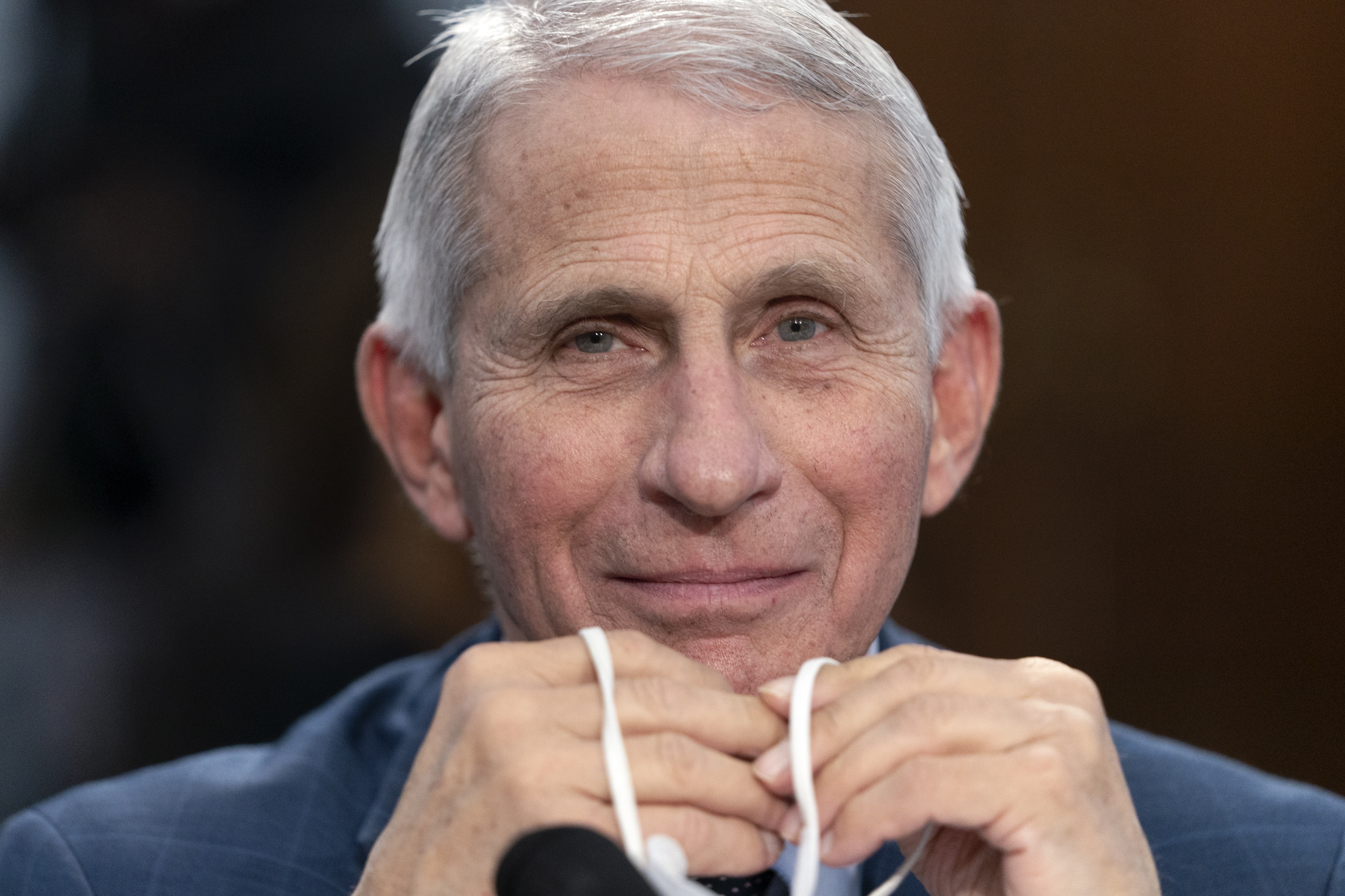 Dr. Anthony Fauci, director of the National Institute of Allergy and Infectious Diseases, holds his face mask as he attends a House subcommittee hearing May 11 on Capitol Hill in Washington. Fauci announced Monday he will depart the federal government in December. 
