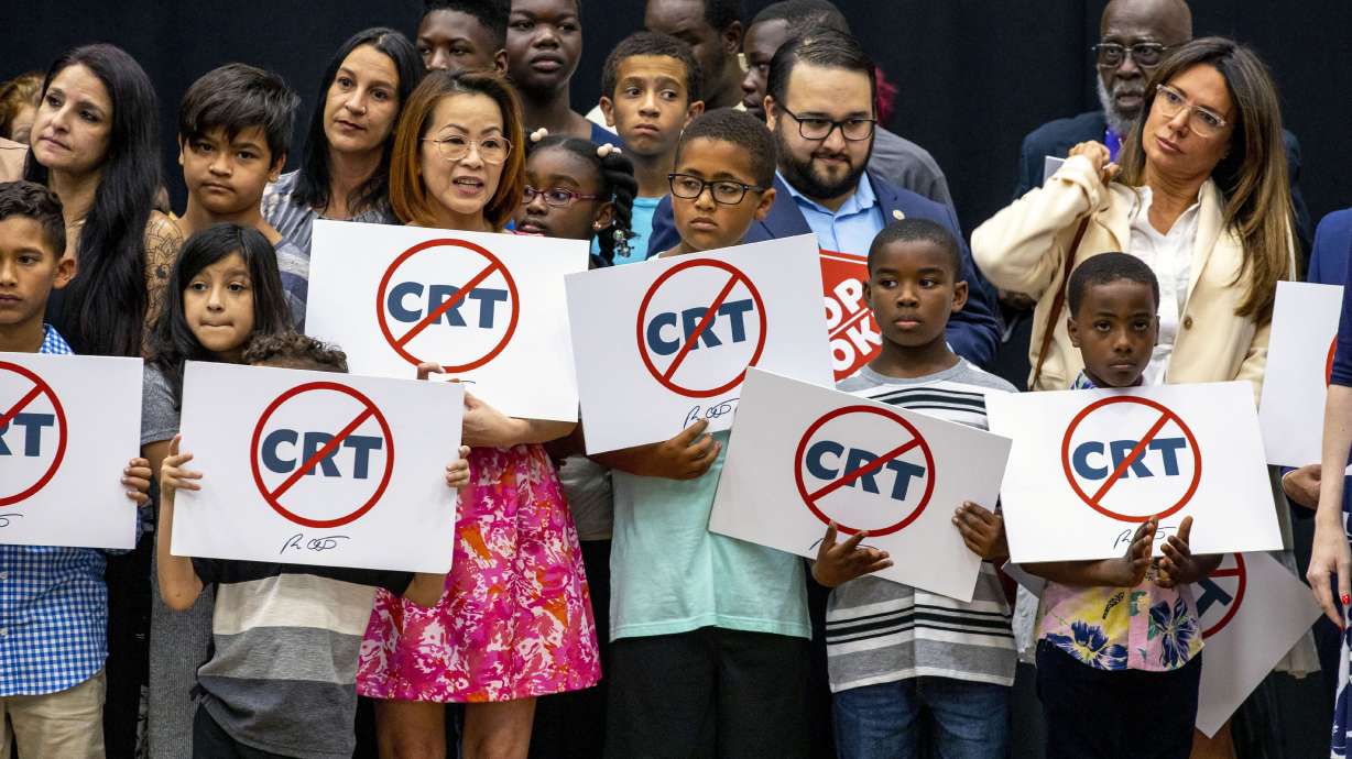 Kids holding signs against Critical Race Theory stand near Florida Gov. Ron DeSantis as he addresses the crowd before publicly signing HB7, “individual freedom,” also dubbed the “stop woke” bill in Hialeah Gardens, Fla., on April 22. A federal judge has blocked part of Florida's Stop WOKE Act.