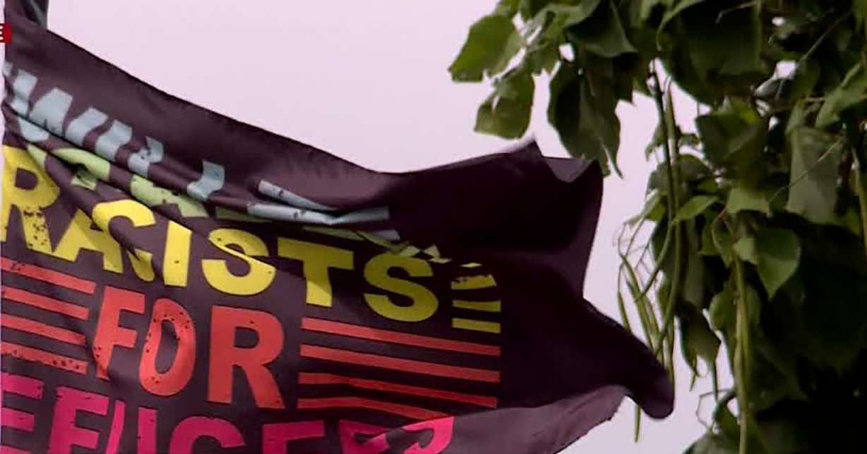 A flag stating "Will trade racists for refugees" flies at Robert Smith's home in Sandy Friday. Smith feels vandals have targeted his lawn due to the flags at his home.