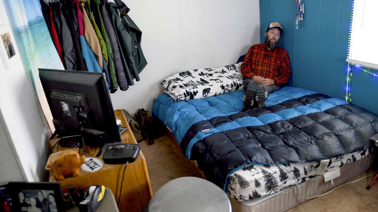 Sean Bailey sits in his bedroom, Aug. 4, in Steamboat Springs, Colo. Bailey, who moved to Steamboat Springs in 2019, has been on a waitlist for three years to get one of Steamboat's affordable housing apartments. He says the 12-foot-by-12-foot space serves as his living room, dining room, den and office.