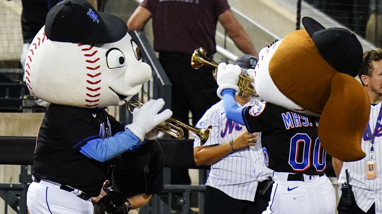 Mr. and Mrs. Met play trumpets as New York Mets reliever Edwin Diaz approaches the pitcher's mound to start the ninth inning of a baseball game against the Philadelphia Phillies, Friday, Aug. 12, 2022, in New York.