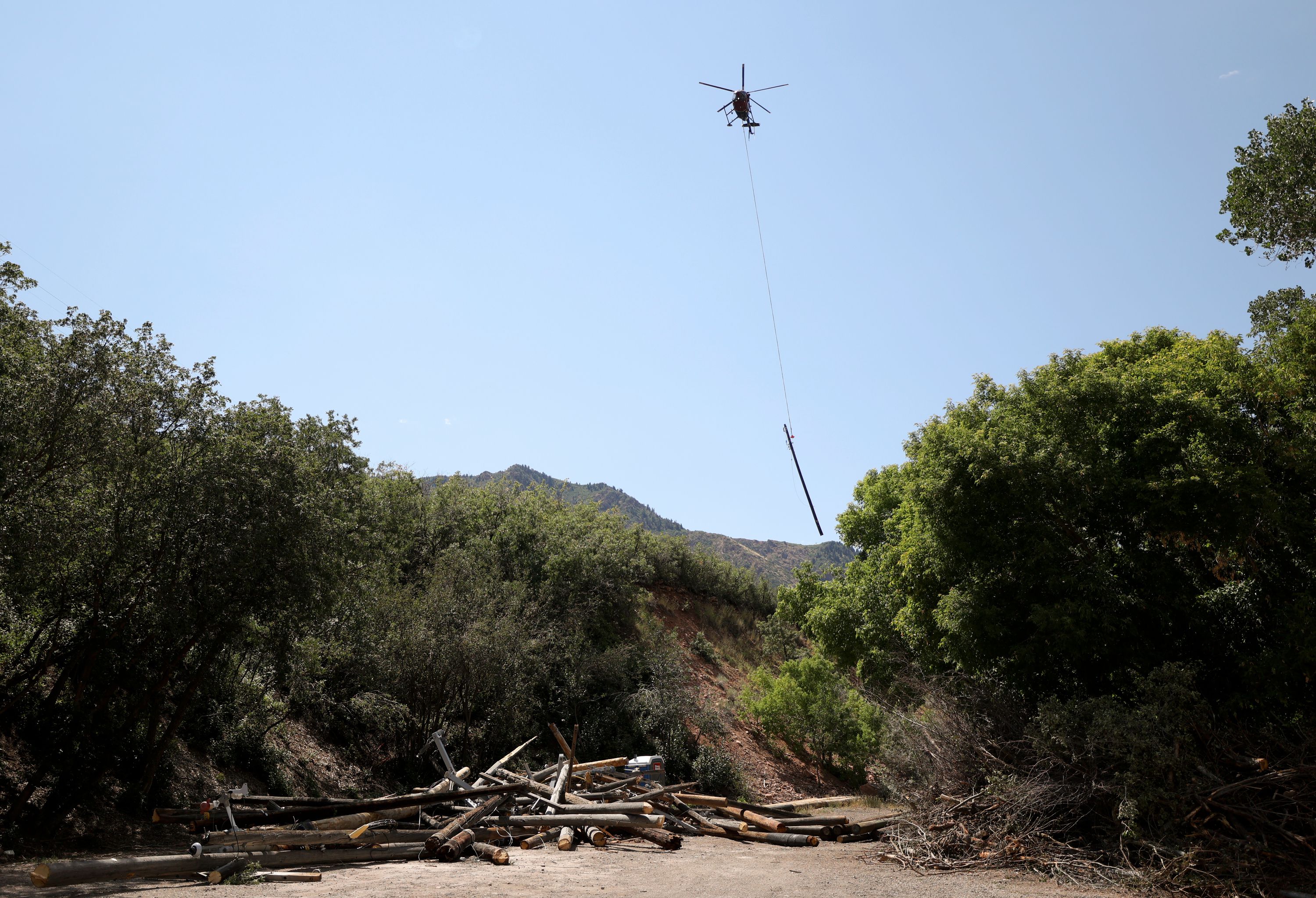 Brock Wilson, Wasatch Helicopter pilot, pulls old utility poles off Mt. Aire after Rocky Mountain Power buried power lines for wildfire mitigation in Salt Lake County on Tuesday.