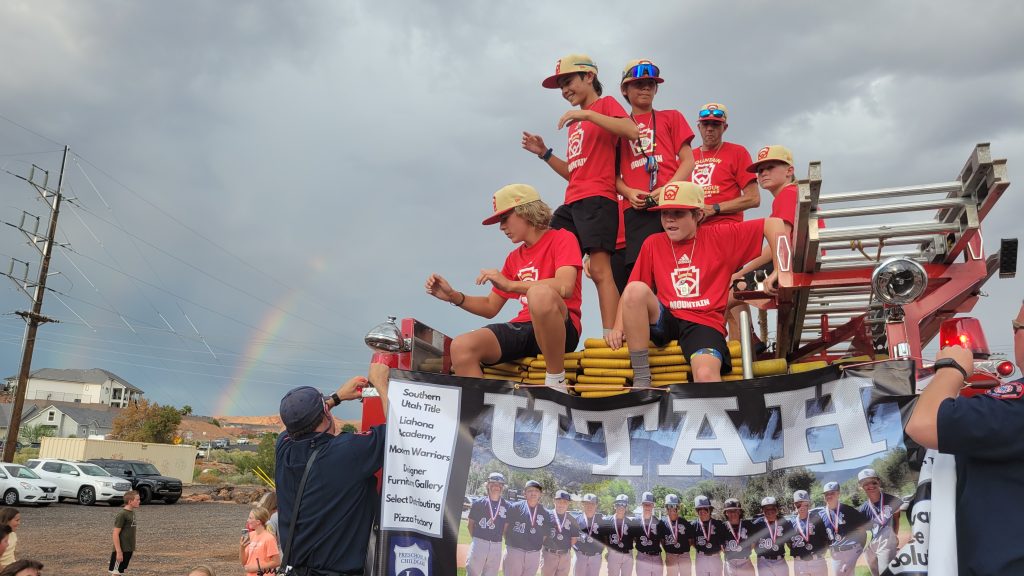 With a faint rainbow in the background, Snow Canyon all-star players arrive on a fire truck during the team's welcome back at the Little League complex from the Little League World Series, Santa Clara, Utah, Wednesday.