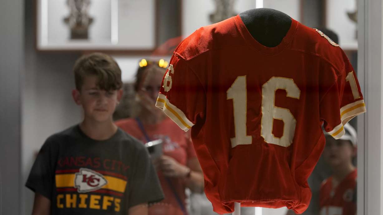 A fan looks at the jersey of former Kansas City Chiefs quarterback Len Dawson before the start of an NFL preseason football game between the Kansas City Chiefs and the Green Bay Packers Thursday, Aug. 25, 2022, in Kansas City, Mo. Dawson, who helped the Kansas City Chiefs to their first Super Bowl title and is in the Pro Football Hall of Fame as a player and broadcaster, died Wednesday at the age of 87.