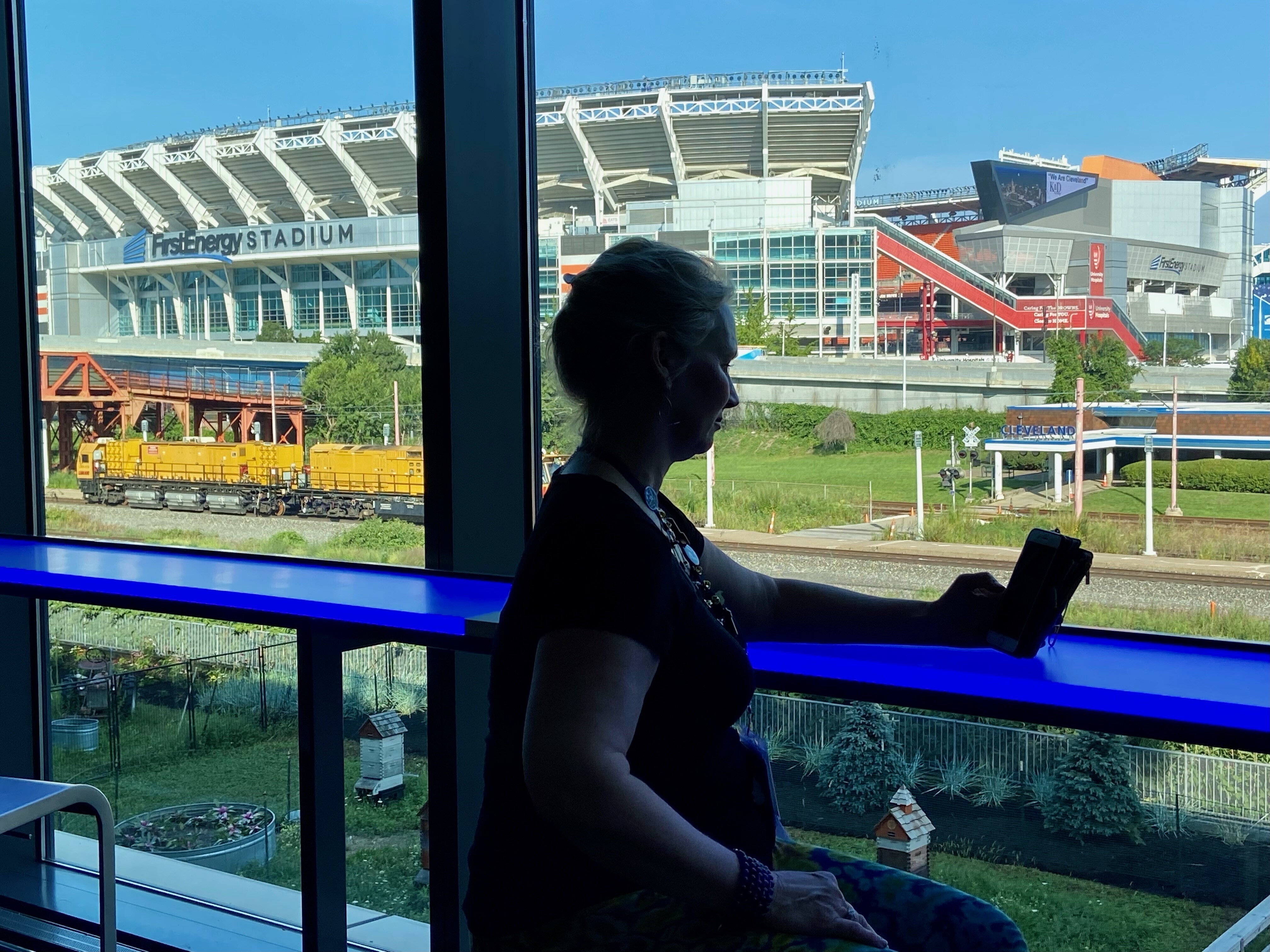 Retired firefighter Michelle Krause checks her phone during a break at the American Massage Therapist Association national convention at the Huntington Convention Center in Cleveland, Ohio, Thursday, Aug. 25, 2022. In the background is FirstEnergy Stadium, home of the Cleveland Browns NFL football team. 