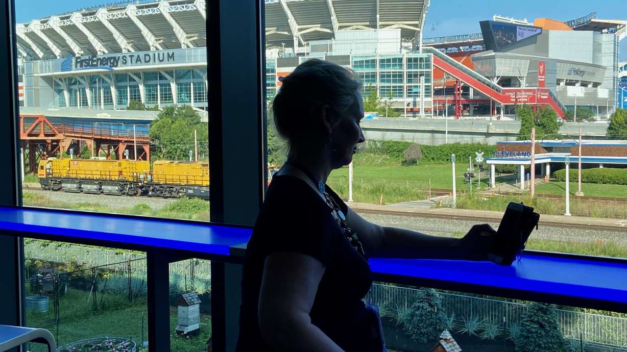 Retired firefighter Michelle Krause checks her phone during a break at the American Massage Therapist Association national convention at the Huntington Convention Center in Cleveland, Ohio, Thursday, Aug. 25, 2022. In the background is FirstEnergy Stadium, home of the Cleveland Browns NFL football team.