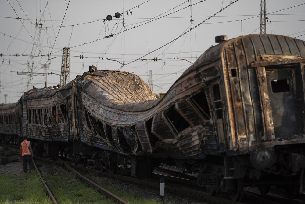 A railway worker stands next to a heavily damaged train after a Russian attack on a train station yesterday during Ukraine's Independence Day in the village of Chaplyne, Ukraine, Thursday.
