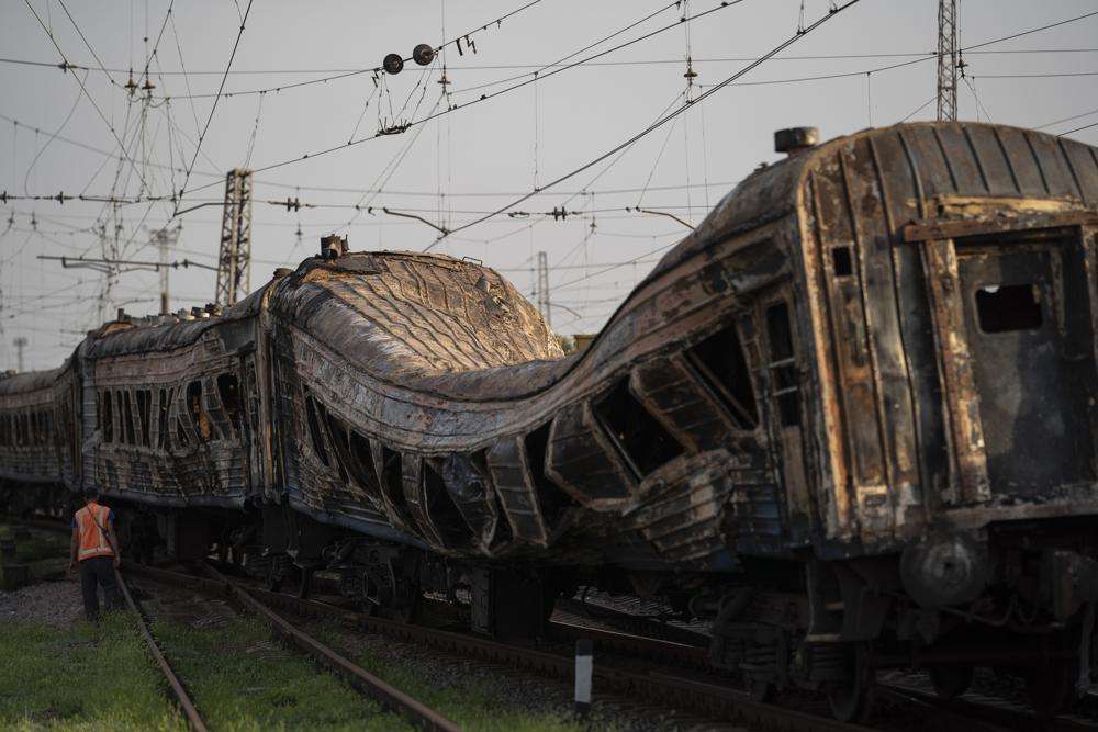 A railway worker stands next to a heavily damaged train after a Russian attack on a train station yesterday during Ukraine's Independence Day in the village of Chaplyne, Ukraine, Thursday.