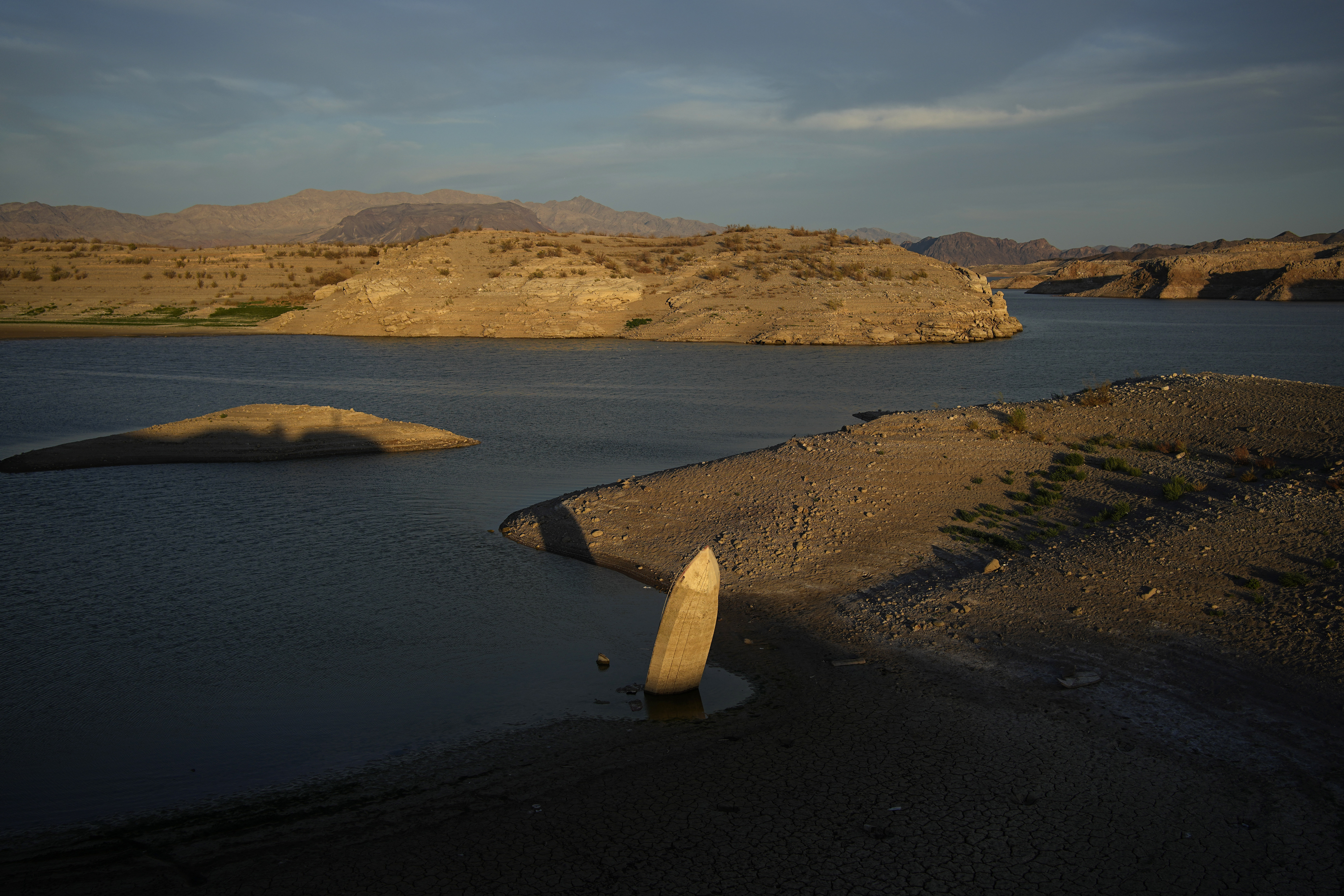 A formerly sunken boat sits upright into the air with its stern stuck in the mud along the shoreline of Lake Mead at the Lake Mead National Recreation Area, on June 10, 2022, near Boulder City, Nevada. A new federal program announced Wednesday seeks to help the struggling reservoir by paying water users to cut their consumption of the Colorado River in Arizona, Nevada and California.