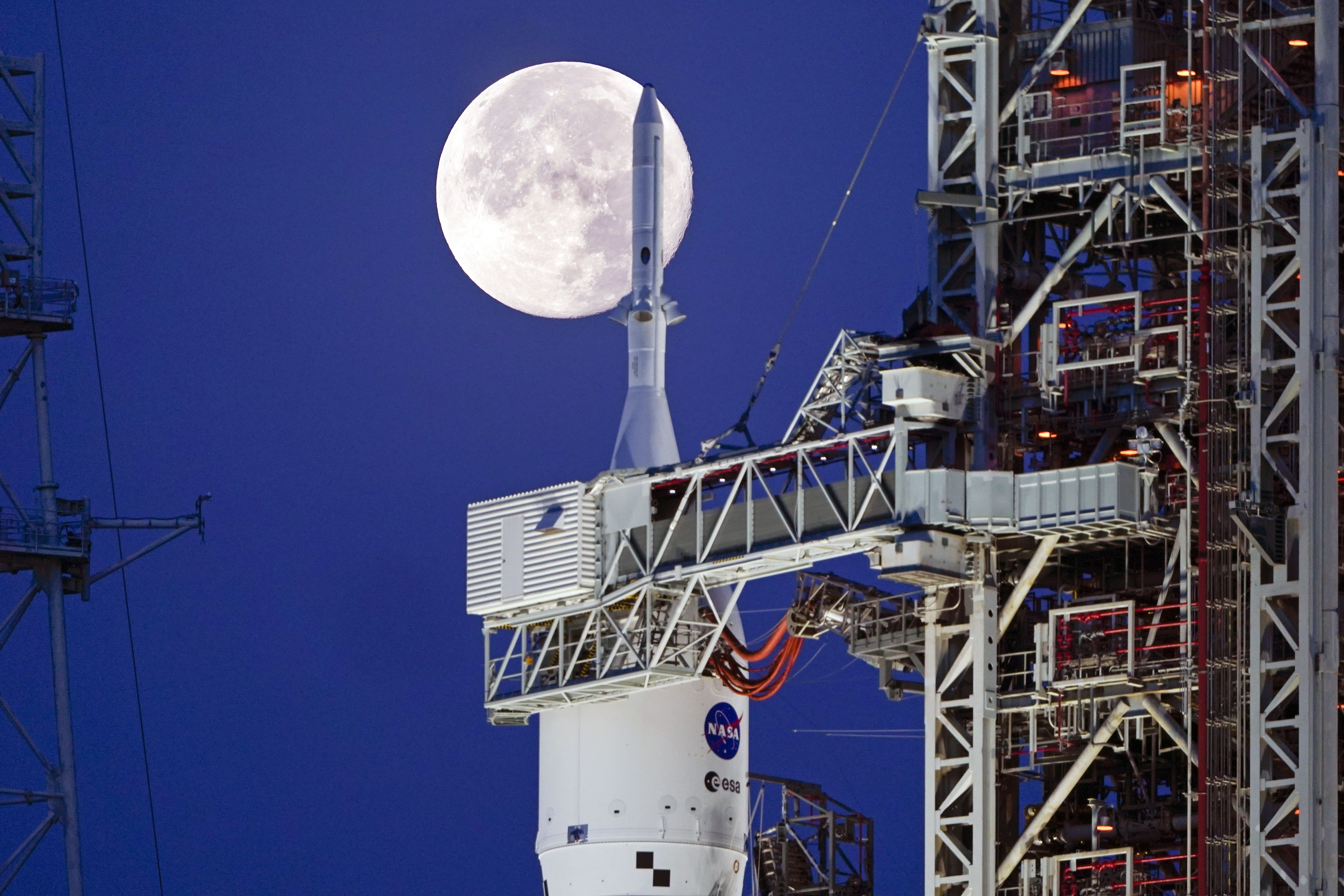 The strawberry supermoon sets in front of the NASA Artemis rocket with the Orion spacecraft aboard on pad 39B at the Kennedy Space Center on June 15, in Cape Canaveral, Fla. NASA's "new" and most-powerful-ever uber rocket, the Space Launch System, is poised on a platform at Florida's Kennedy Space Center, ready to lift off the first step toward putting human explorers back on the moon.