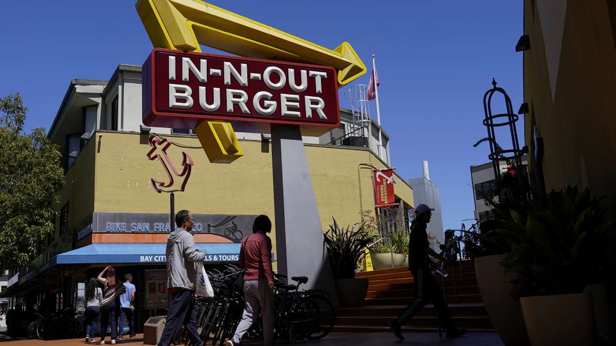 Pedestrians walk below an In-N-Out Burger restaurant sign in San Francisco on Thursday. More than a half-million California fast-food workers are pinning their hopes on a groundbreaking proposal that would give them increased power and protections.