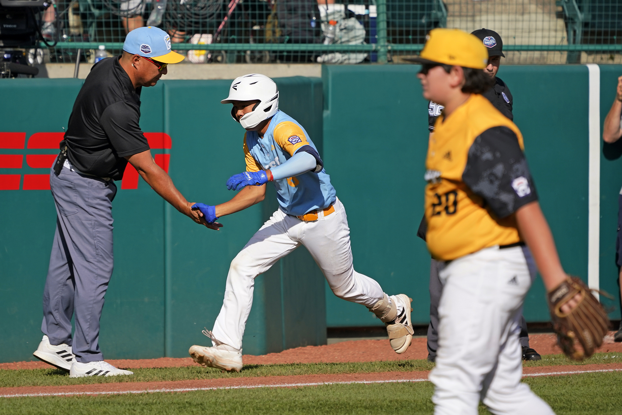 Honolulu's Rustan Hiyoto, center, rounds third to greetings from manager Gerald Oda, left, after hitting a two-run home run off Nolensville, Tenn.'s Trent McNeil (20) in the fourth inning of the United States Championship baseball game at the Little League World Series tournament in South Williamsport, Pa., Saturday, Aug. 27, 2022. 