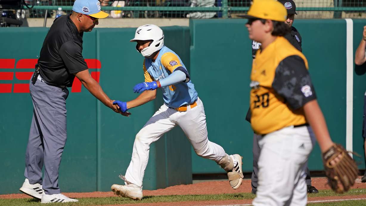 Honolulu's Rustan Hiyoto, center, rounds third to greetings from manager Gerald Oda, left, after hitting a two-run home run off Nolensville, Tenn.'s Trent McNeil (20) in the fourth inning of the United States Championship baseball game at the Little League World Series tournament in South Williamsport, Pa., Saturday, Aug. 27, 2022.