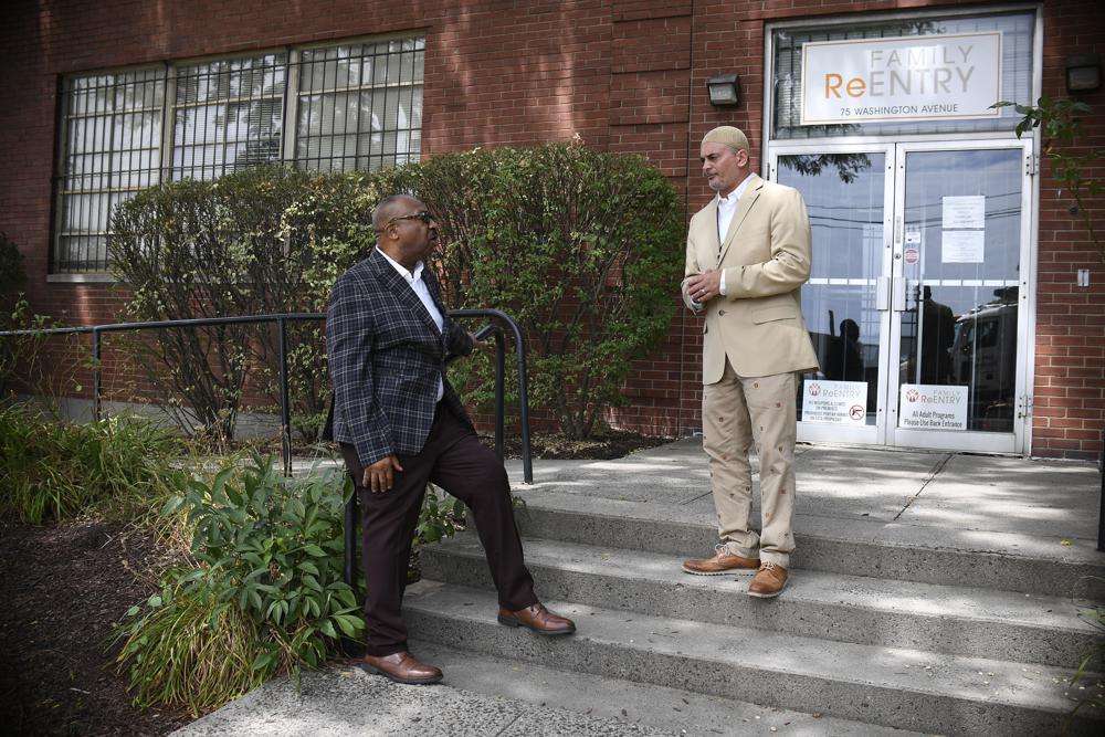 In this Aug. 10 photo, Fred Hodges, left, and Da'ee McKnight talk outside where they work at Family ReEntry a reentry support group aiming to break cycles of violence, crime and incarceration in Bridgeport, Conn. Hodges and McKnight are former Connecticut inmates who have been paying for cost of their incarceration.