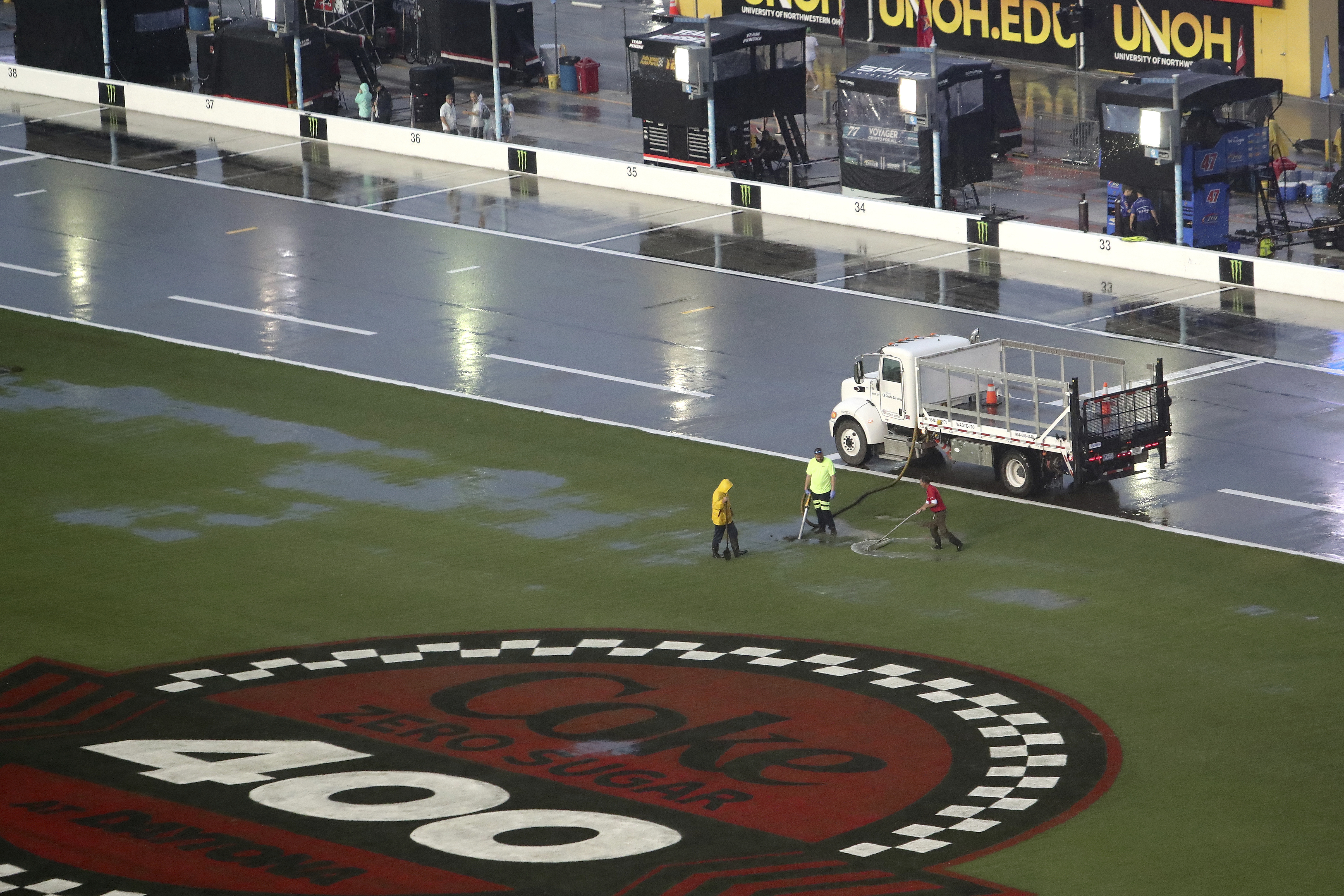 Track workers attempt to clear some of the water off of the infield grass as rain falls before a NASCAR Cup Series auto race at Daytona International Speedway, Saturday, Aug. 27, 2022, in Daytona Beach, Fla. 