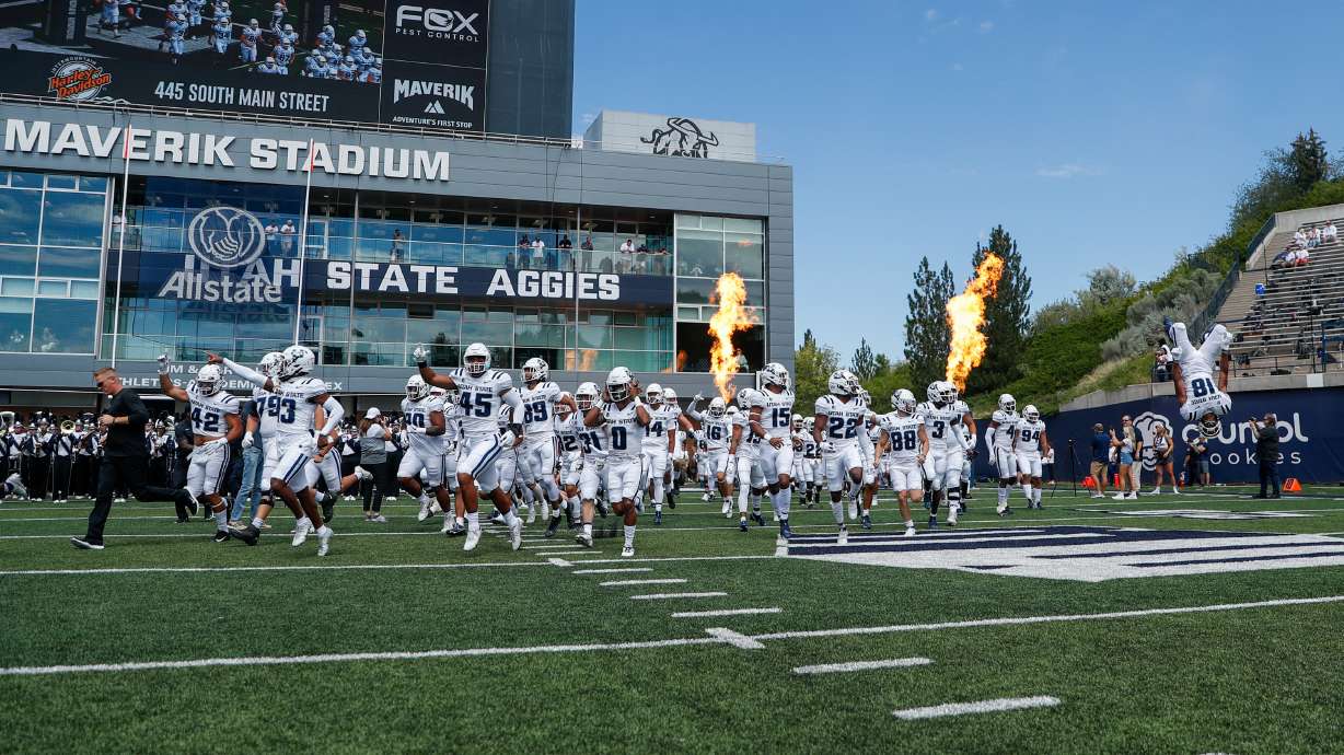 The Utah Aggies storm the field before playing the UConn Huskies at the Maverik Stadium in Logan on Saturday, Aug. 27, 2022.