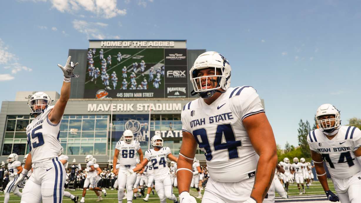 The Utah Aggies storm the field before playing the UConn Huskies at the Maverik Stadium in Logan on Saturday, Aug. 27, 2022.