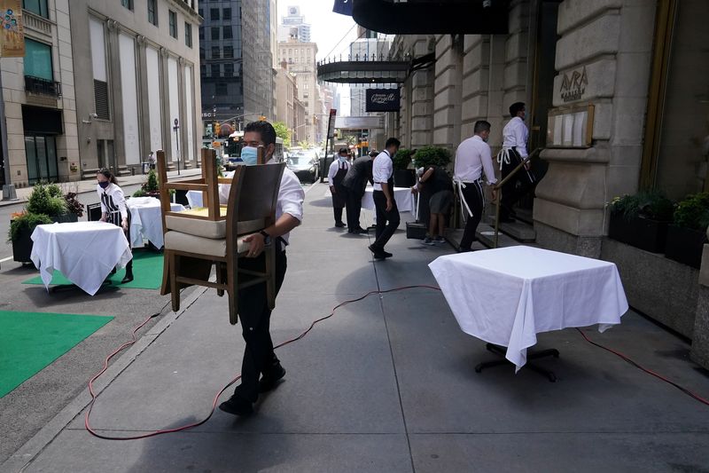 A waiter sets up tables in front of a restaurant on a street on the first day of the phase two re-opening of businesses following the outbreak of COVID-19, in New York City, June 22, 2020. Whether they are selling burgers, pizza or pancakes, major U.S. restaurant chains are short-staffed — and they expect to stay that way.