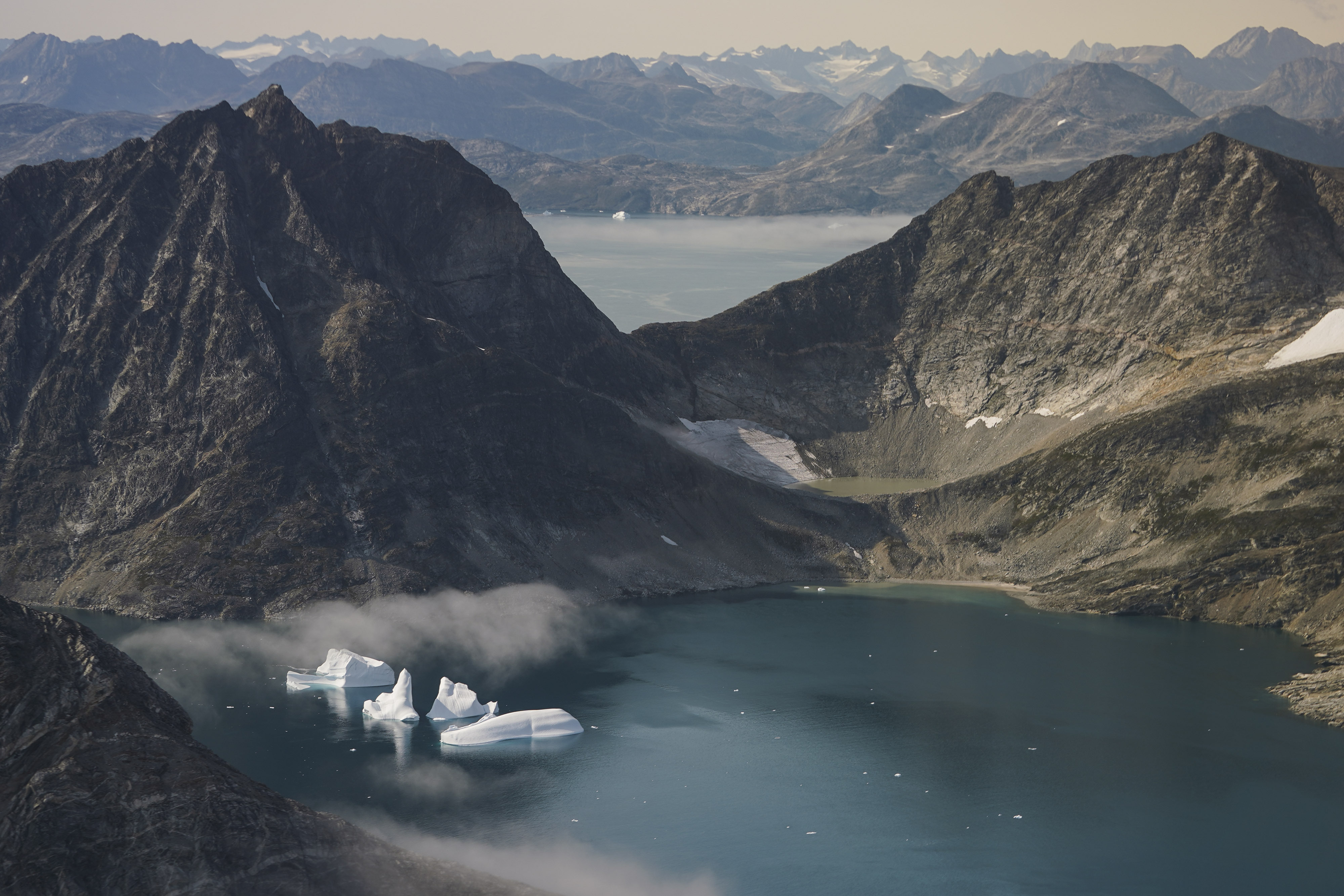 Icebergs are seen through a window of an airplane carrying NASA scientists as they fly on a mission to track melting ice in eastern Greenland on Aug. 14, 2019. Zombie ice from the massive Greenland ice sheet will eventually raise global sea level by at least 10 inches on its own, according to a study released Monday.