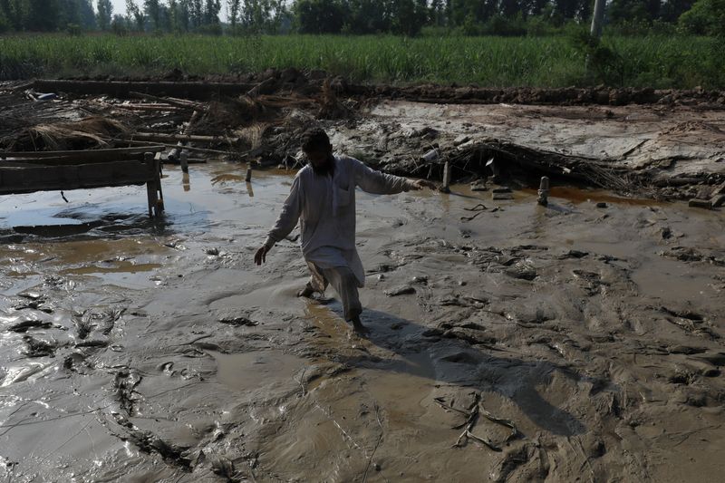 A man walks amid dirt at his damaged house, following rains and floods during the monsoon season in Nowshera, Pakistan, Tuesday.