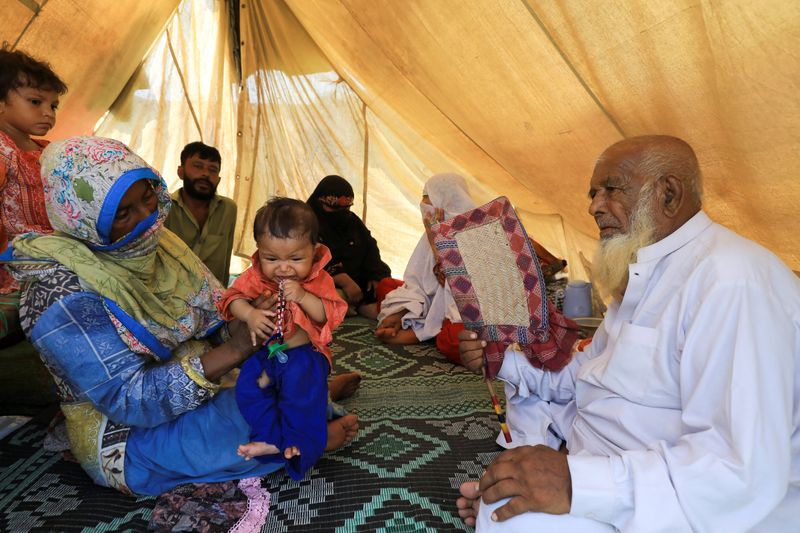 A family sits in a tent while taking refuge in a relief camp, following rains and floods during the monsoon season in Charsadda, Pakistan, Tuesday.
