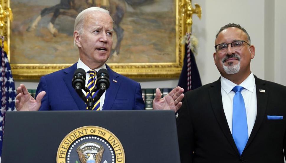 President Joe Biden speaks about student loan debt forgiveness in the Roosevelt Room of the White House, Aug. 24 in Washington. Education Secretary Miguel Cardona listens at right.
