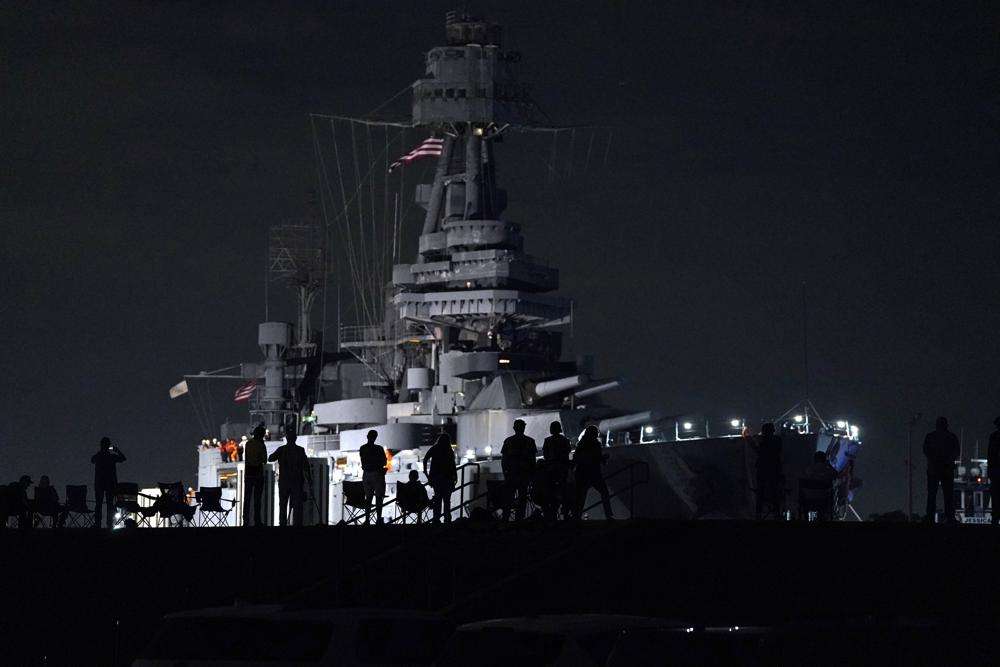 People watch as the USS Texas is moved from the dock Wednesday, in La Porte, Texas. The vessel, which was commissioned in 1914 and served in both World War I and World War II, is being towed down the Houston Ship Channel to a dry dock in Galveston where it will undergo an extensive $35 million repair.