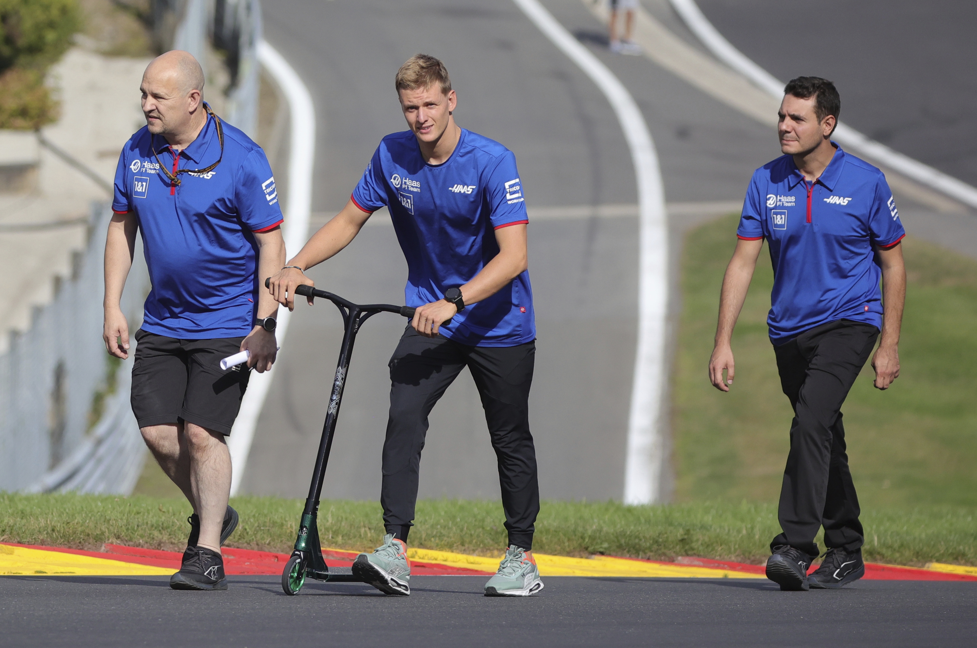 Haas driver Mick Schumacher of Germany, center, walks on the track with his team ahead of the Formula One Grand Prix at the Spa-Francorchamps racetrack in Spa, Belgium, Thursday, Aug. 25, 2022. The Belgian Formula One Grand Prix will take place on Sunday.