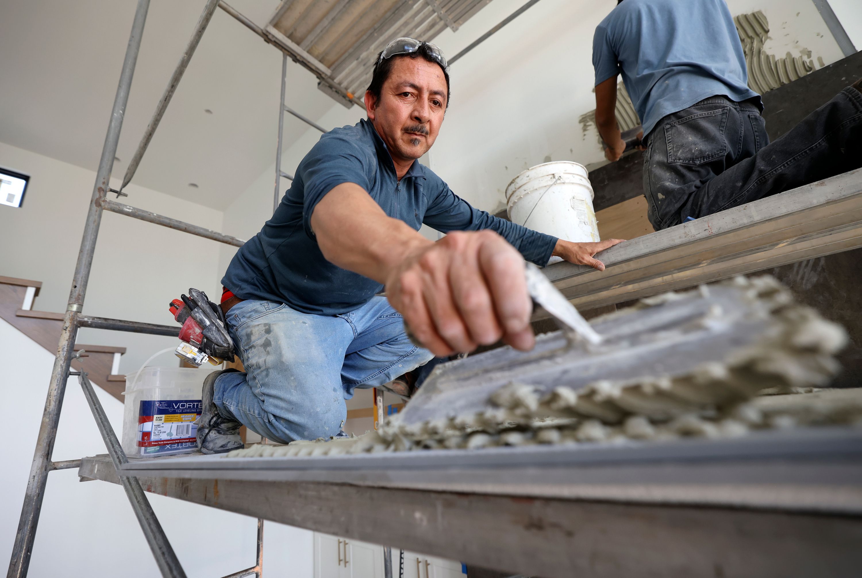 Salvador Vazquez, with Reyes Tile, installs tile above a fireplace in a Steven Dailey Construction home in Draper on Thursday.