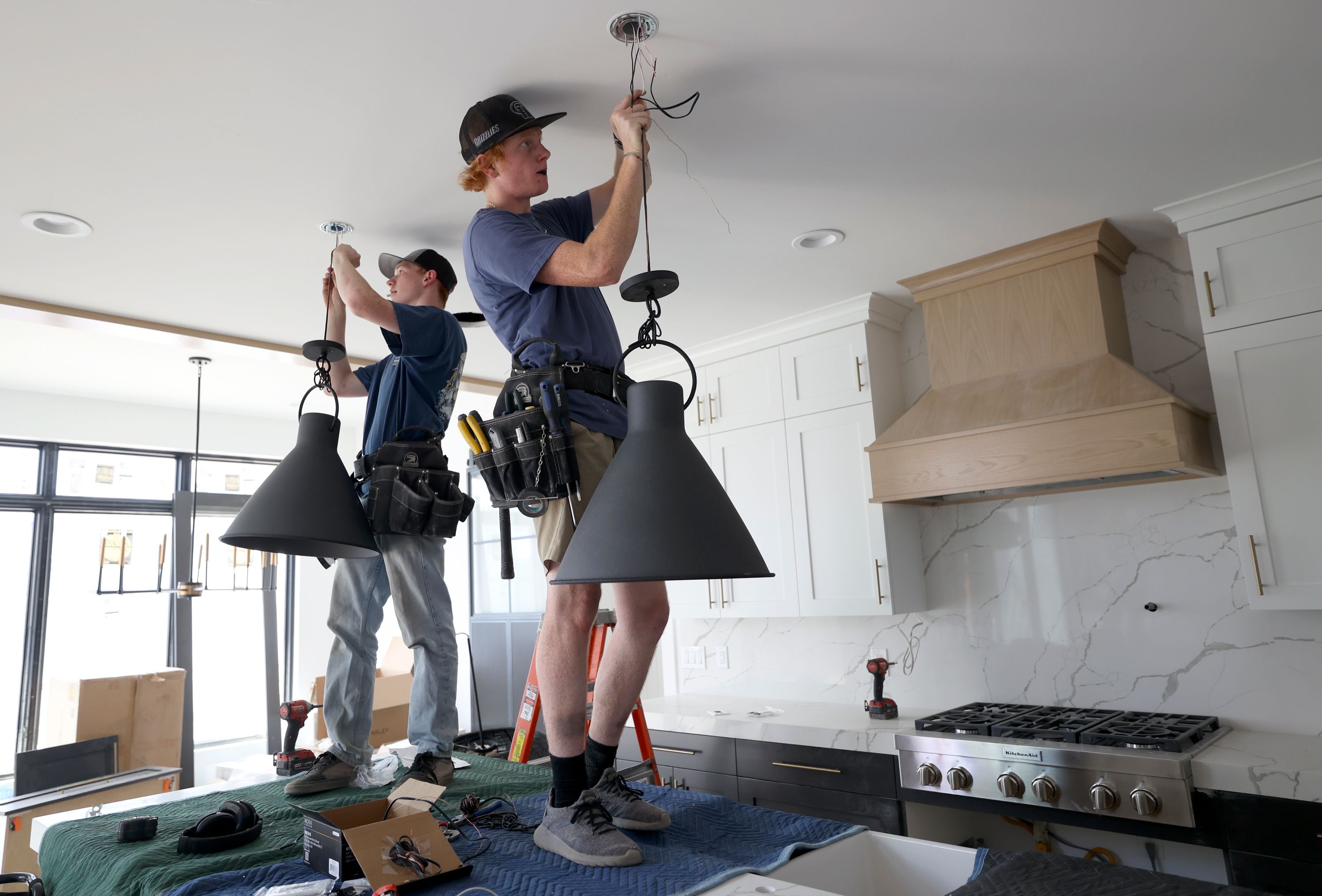 Rentmeister Electric electricians Mason Omer and Isaac McCombs install lights in a Steven Dailey Construction home in Draper on Thursday.