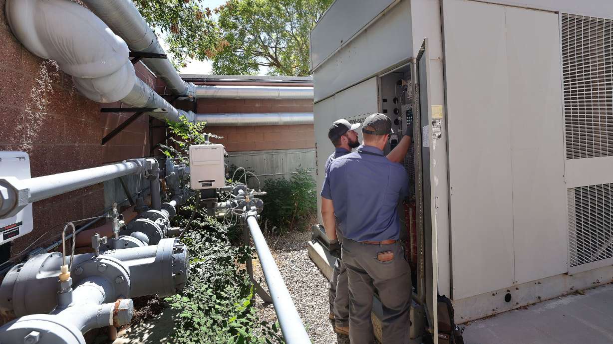 Tooele School District HVAC techs Seth Anderson and Dalton Rydalch look over the chiller unit that broke down and was repaired at Tooele High School in Tooele on Wednesday. Students were dismissed from school.