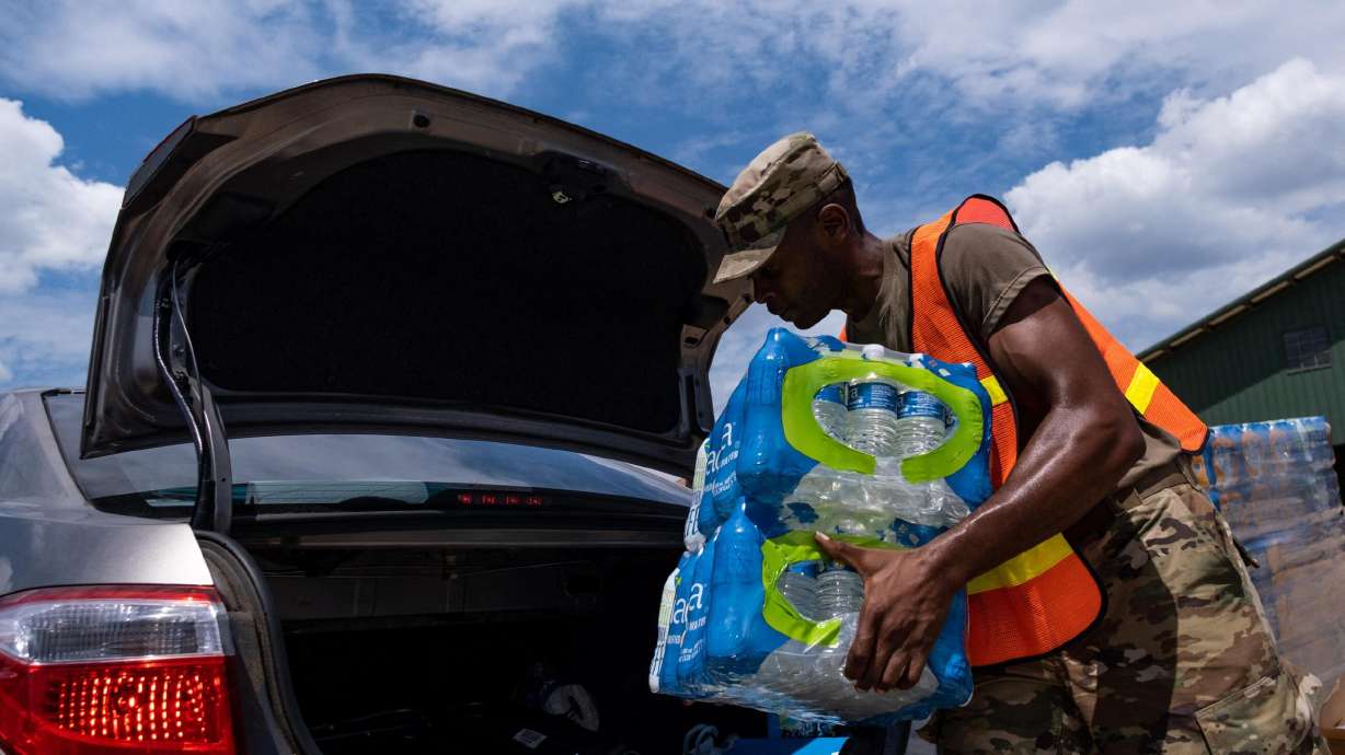 The situation remains dire for many Jackson, Mississippi, residents as the city enters the sixth day since a major water plant failed, and pictured, a member of the National Guard places water cases in Jackson, Mississippi, on Saturday.