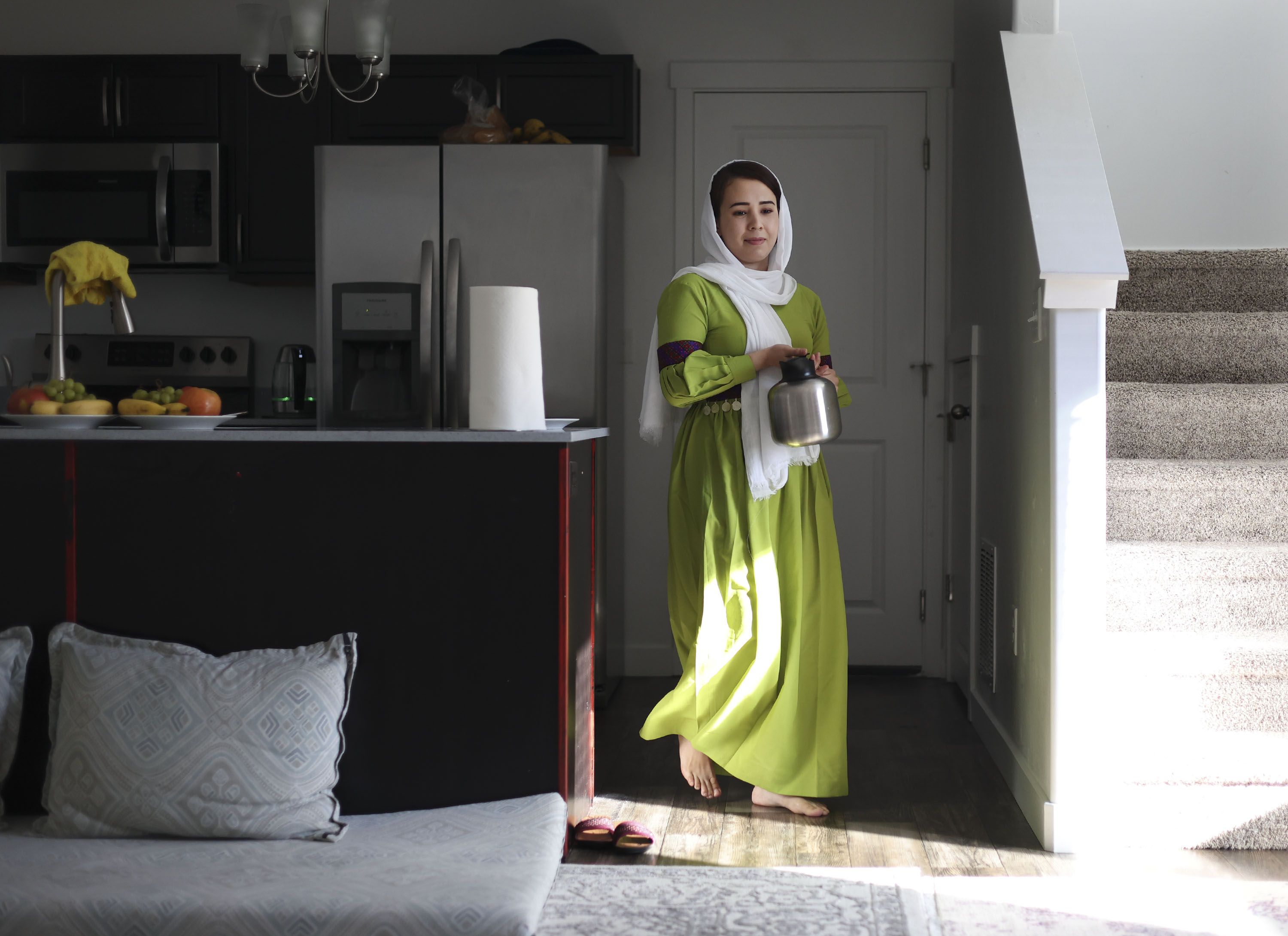 Nazdanah carries a pot of tea in her Herriman home on Wednesday. Nazdanah recently arrived in Utah after being stuck in Afghanistan for almost a year.