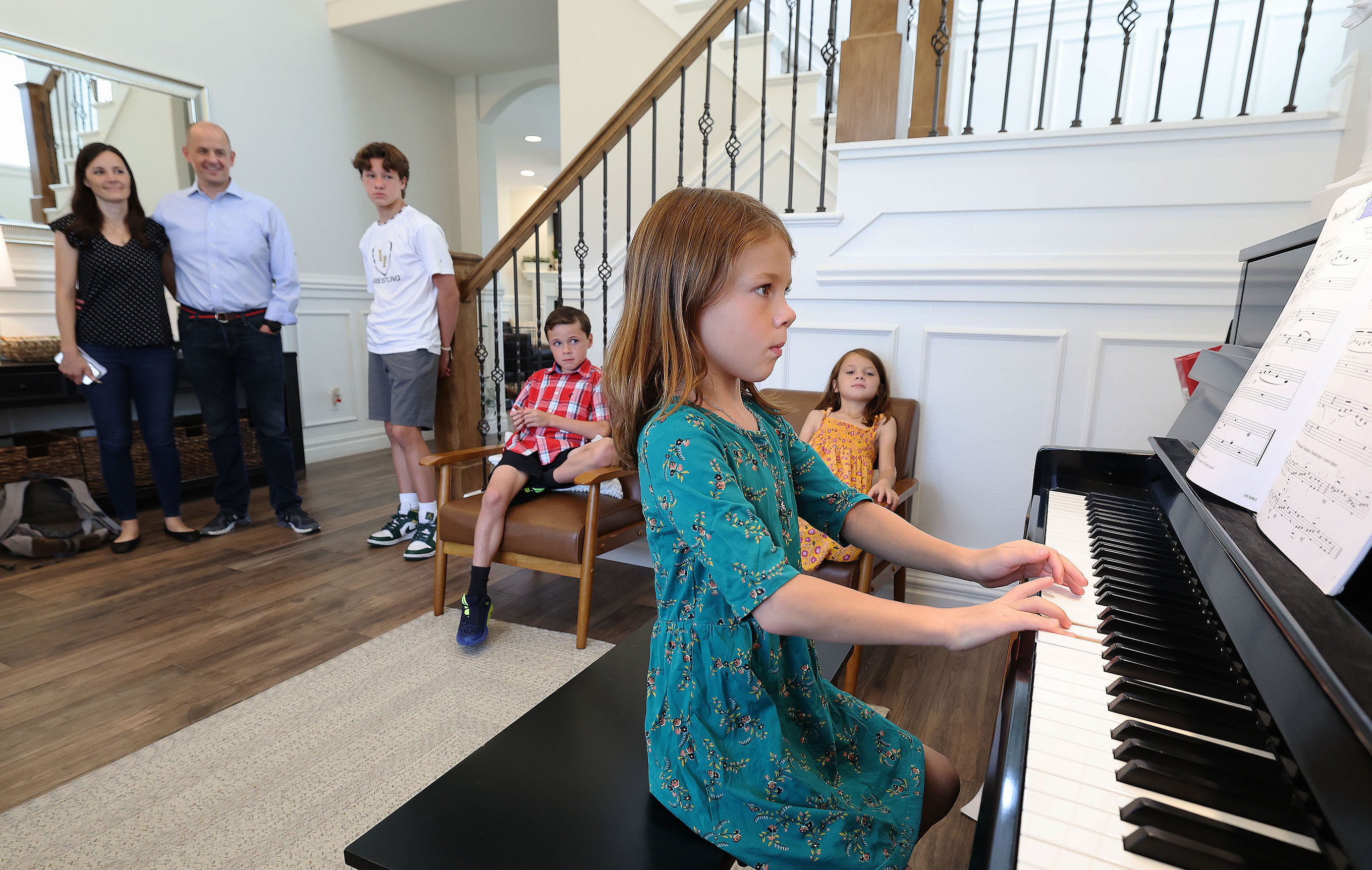 Emily McMullin, left, and her husband, Evan, listen to their daughter Maylee play the piano at their home in Highland on Aug. 5. Evan McMullin is running for U.S. Senate.