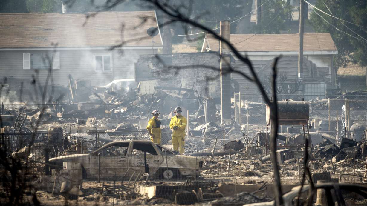 Firefighters survey homes on Wakefield Avenue destroyed by the Mill Fire on Saturday in Weed, Calif.